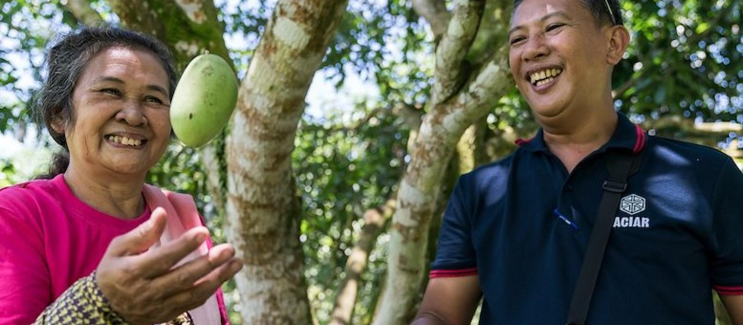 A man and woman hold freshly picked mangoes