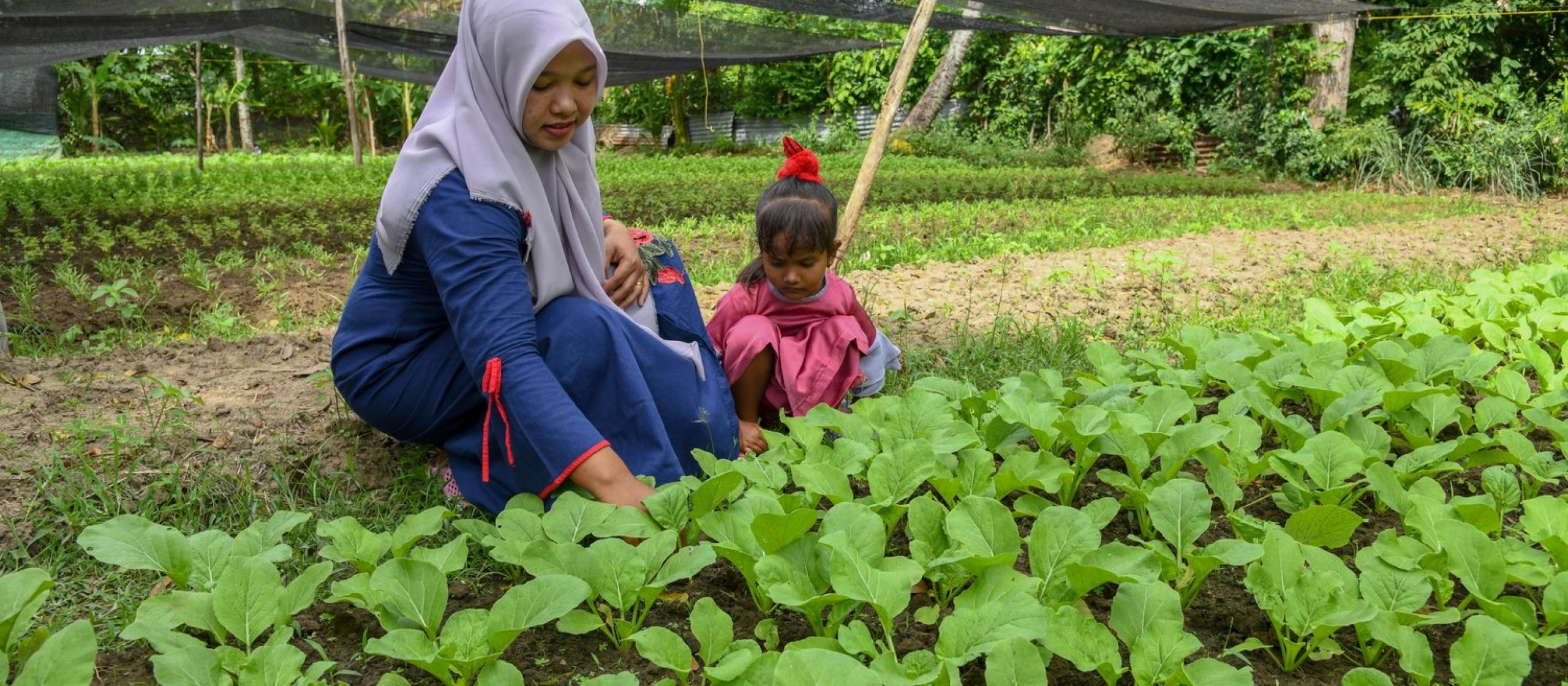mother and daughter tending crops