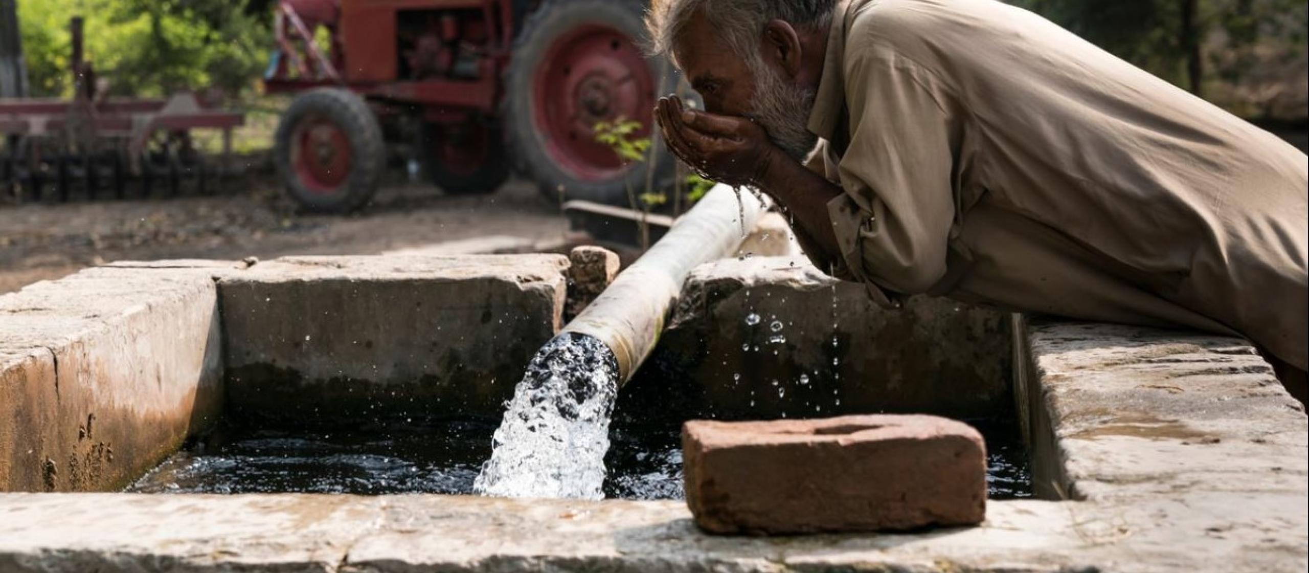 man drinking from well