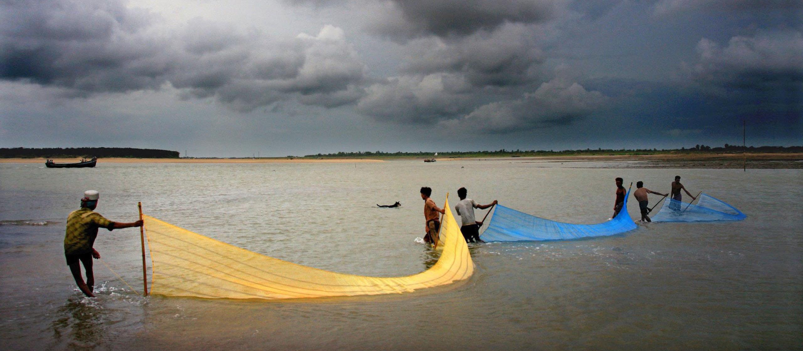 People pulling fishing nets into the ocean