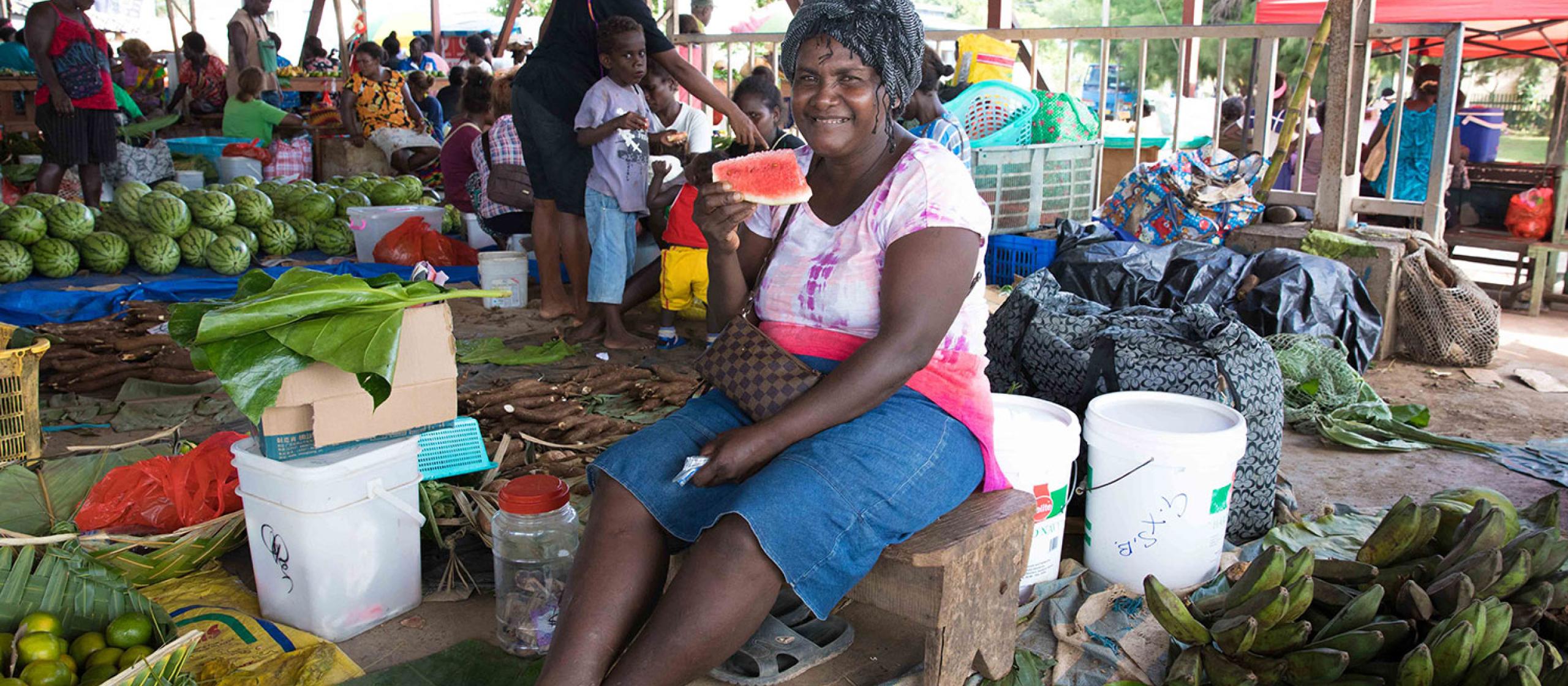 Woman eating watermelon in a fruit market