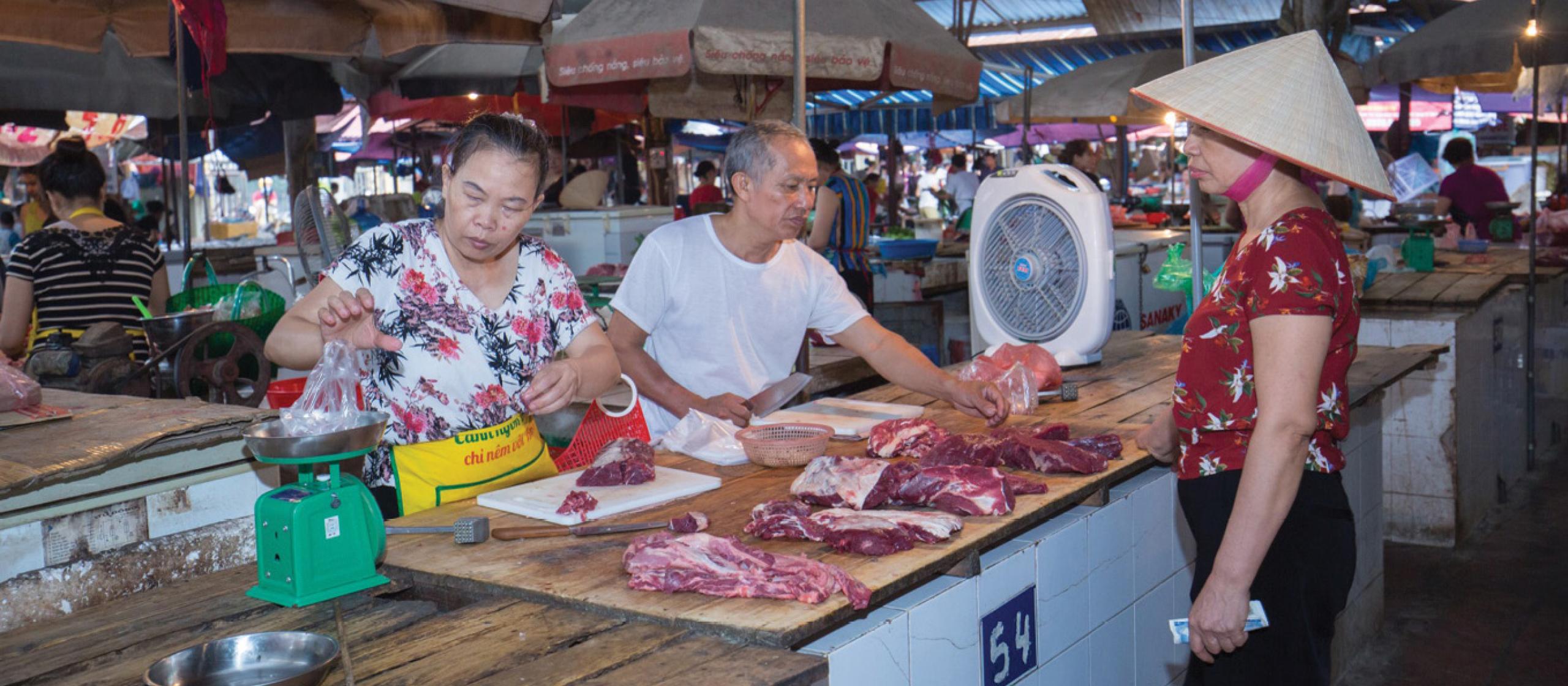 People inspecting pork at a market