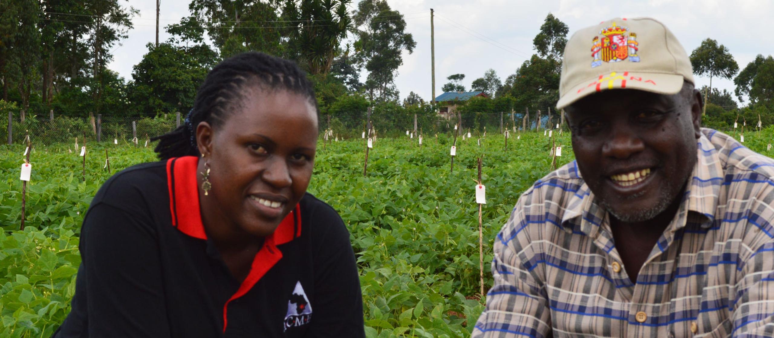 A man and a woman sitting down looking to camera in a vegetable crop