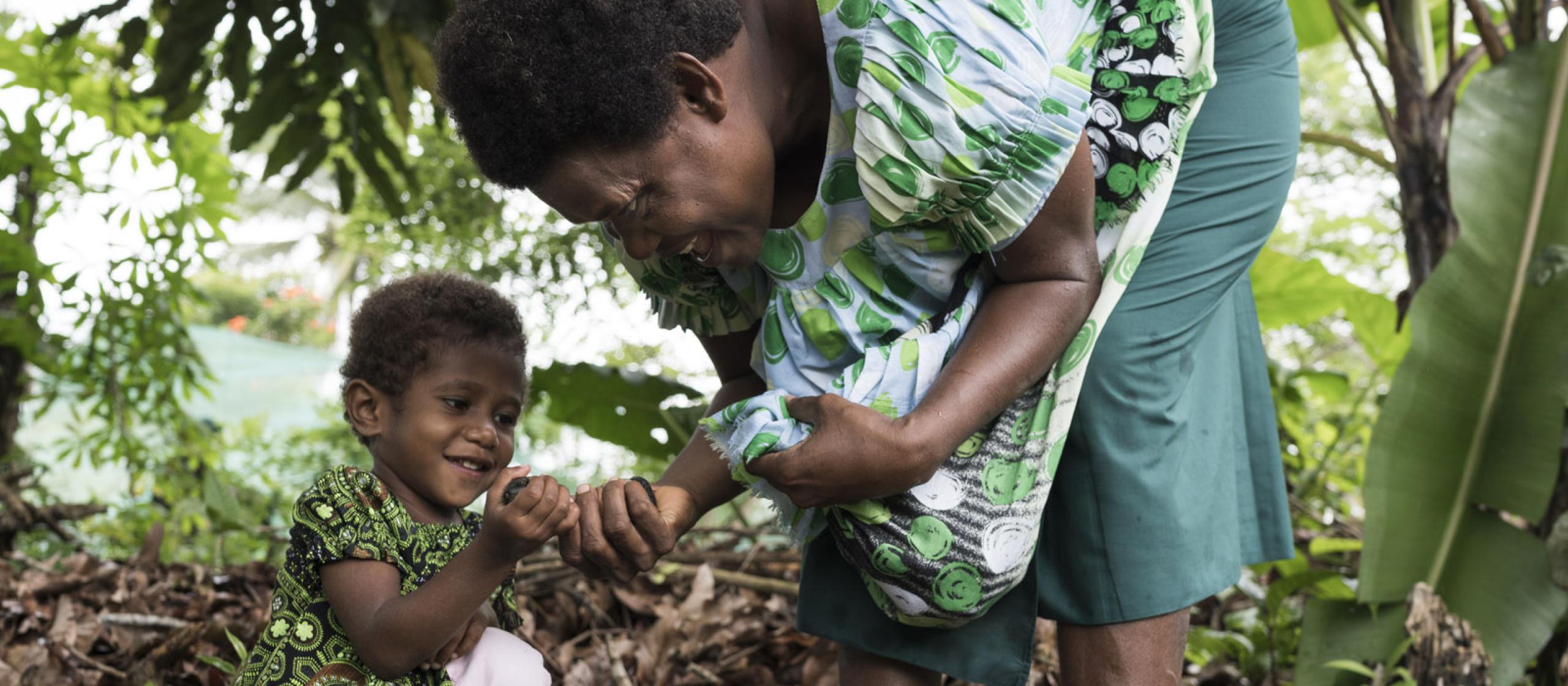 Woman and child collecting nuts in forest