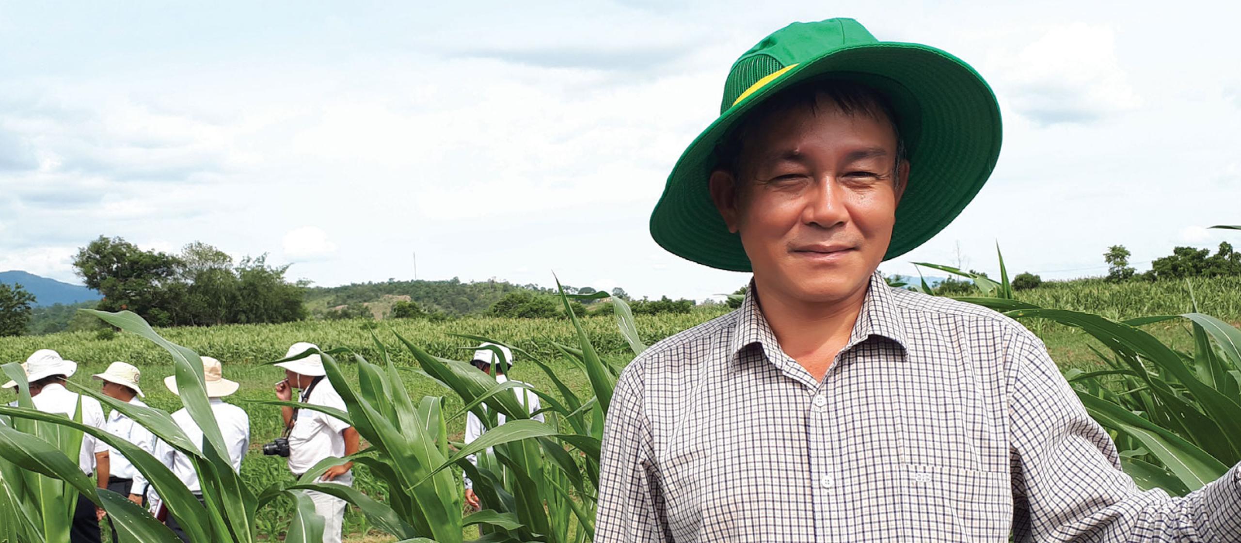 man in green hat standing in green field of maize