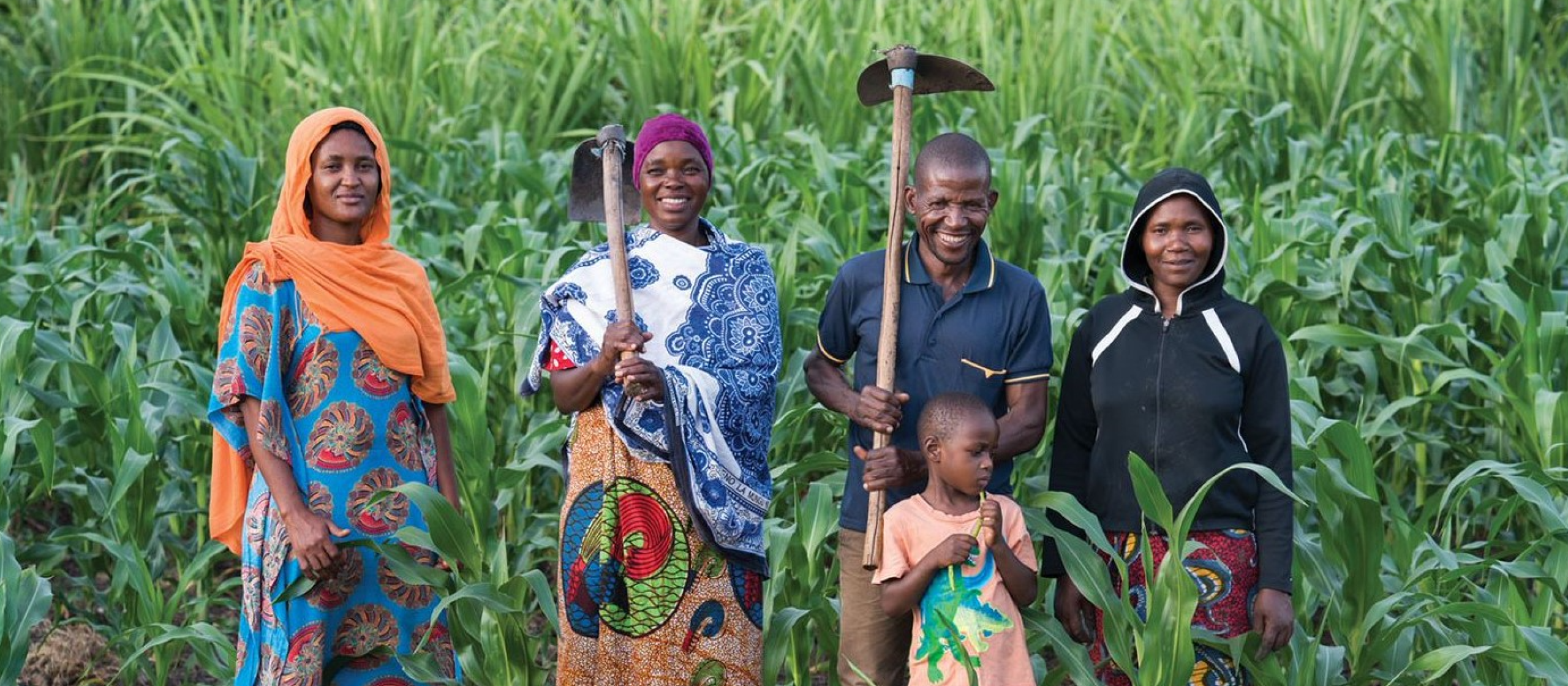 A family of farmers in a field with farming tools