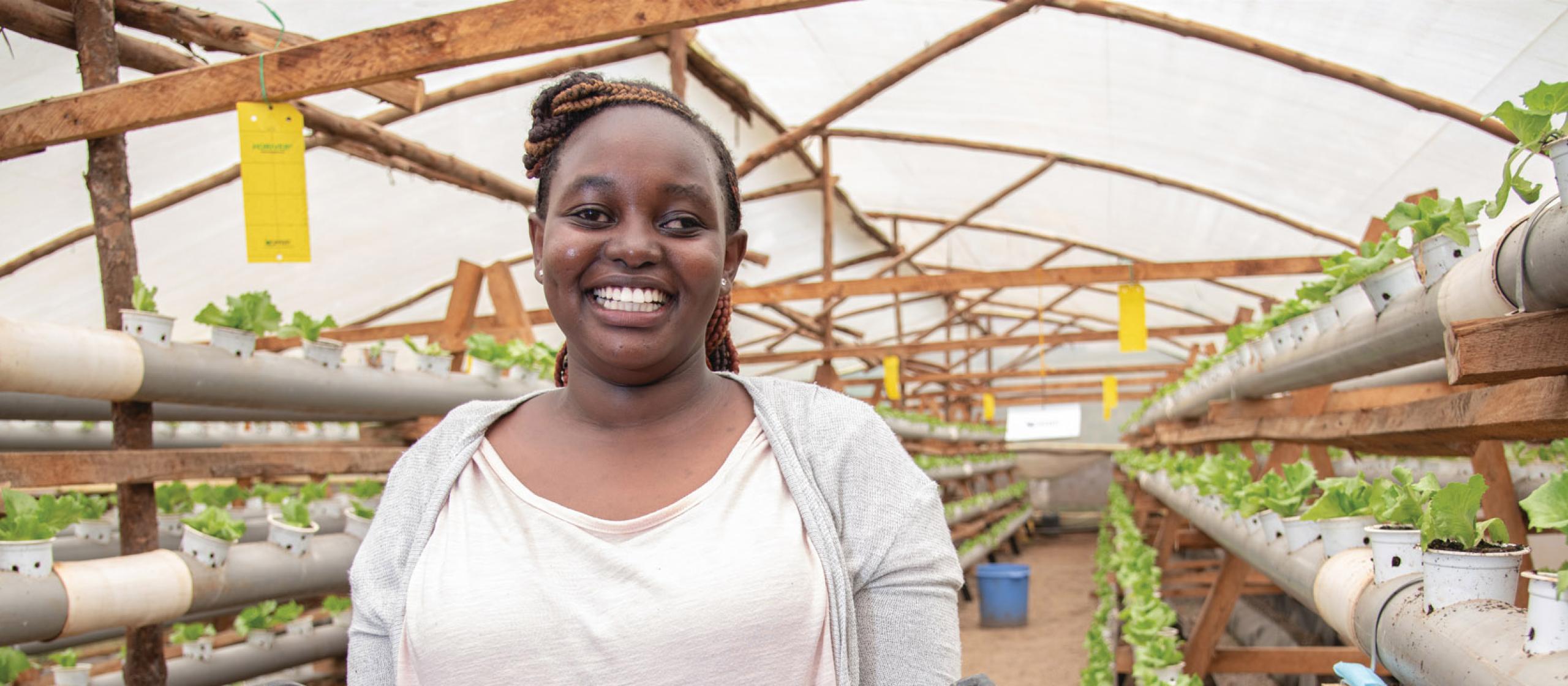 A smiling woman standing in greenhouse