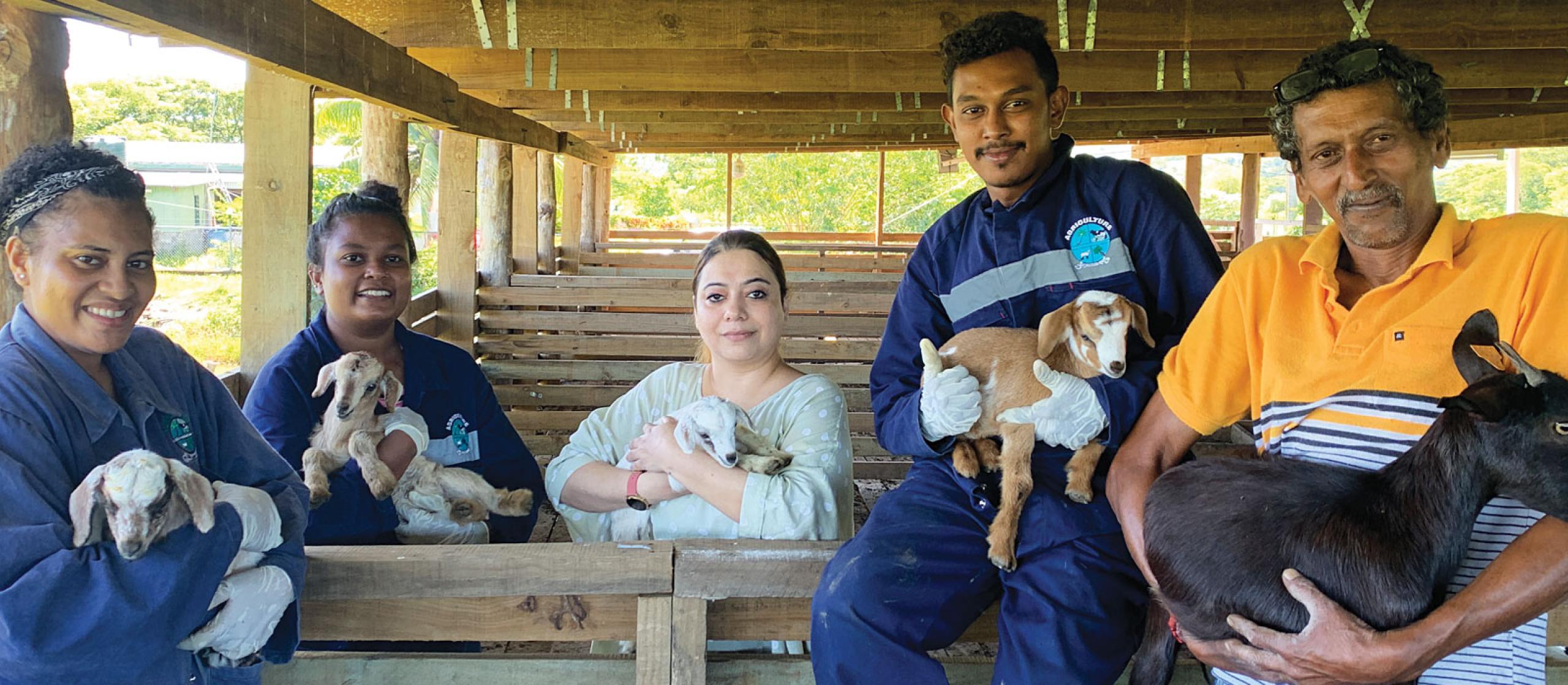 Group of 5 people holding small goats