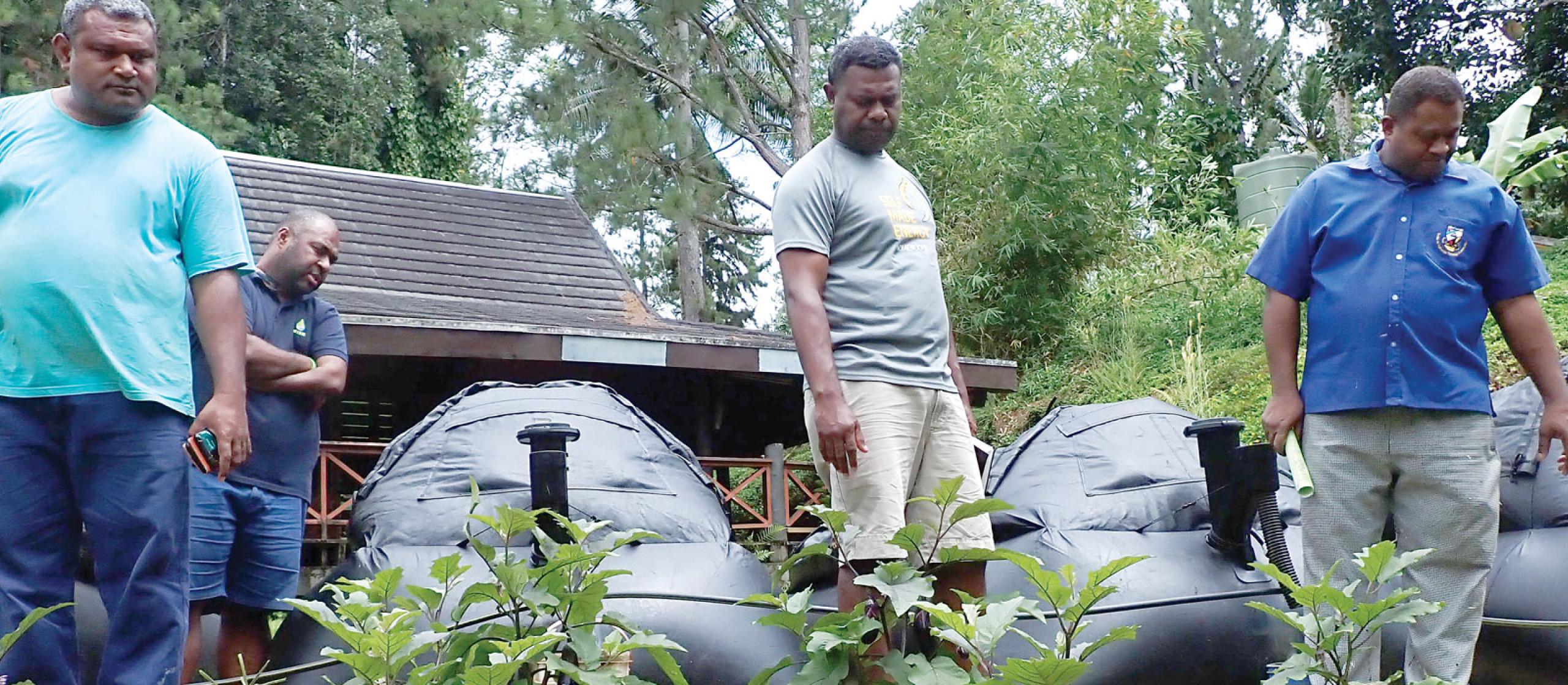 a group of men looking at plants in front of biodigesters