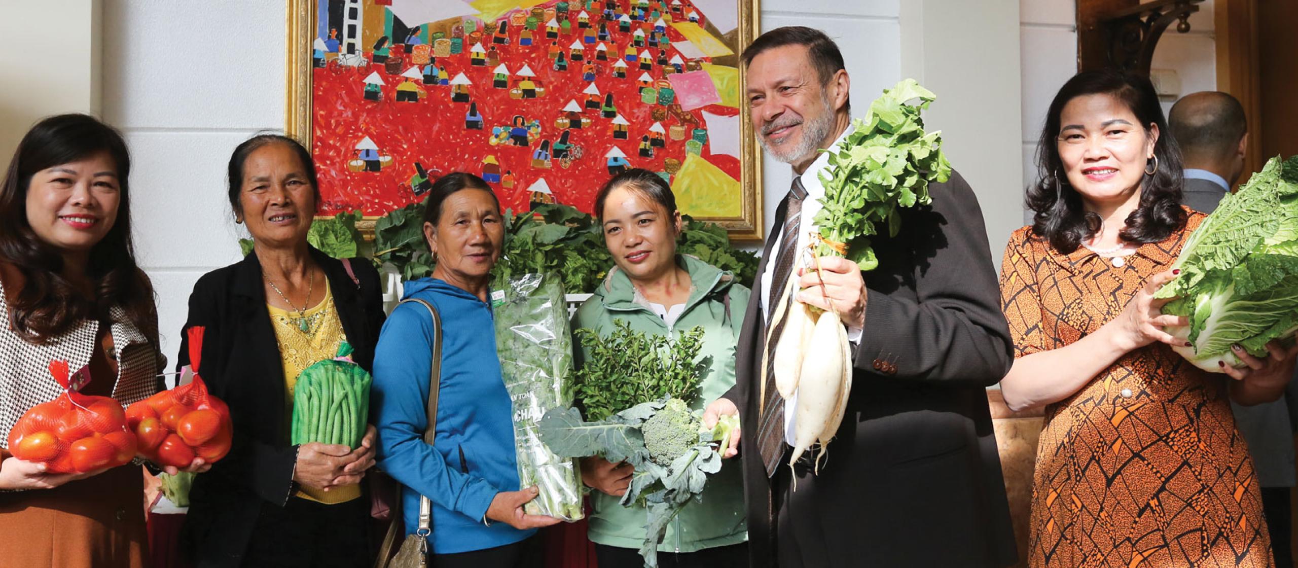 a group of farmers holding vegetable in formal dress in a building.