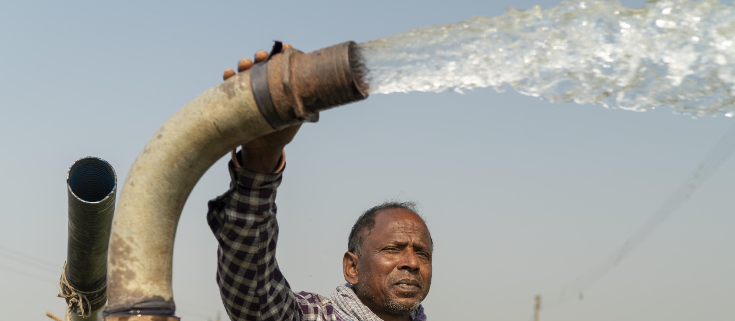 Man holding a water pump that is spraying water