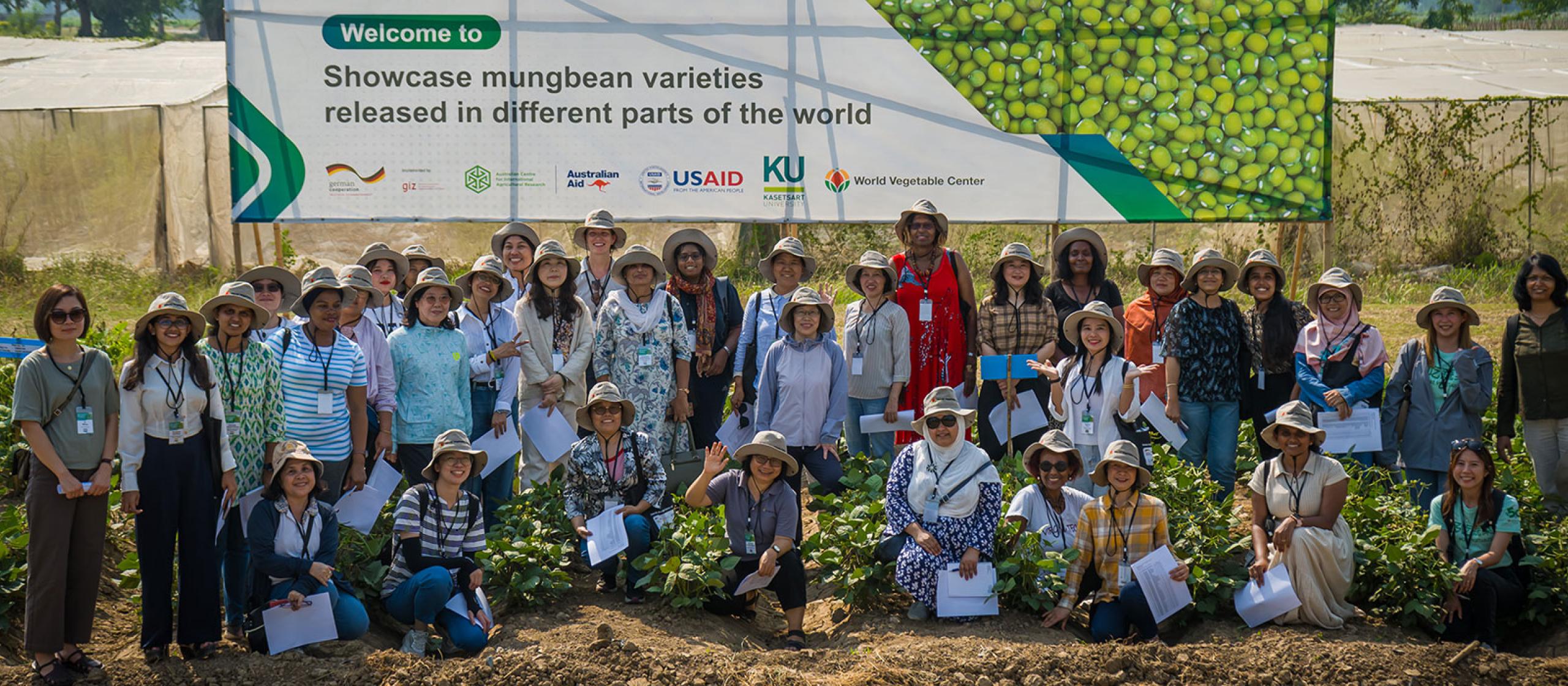 A large group of people, mostly wearing hats outdoors in front of a large sign