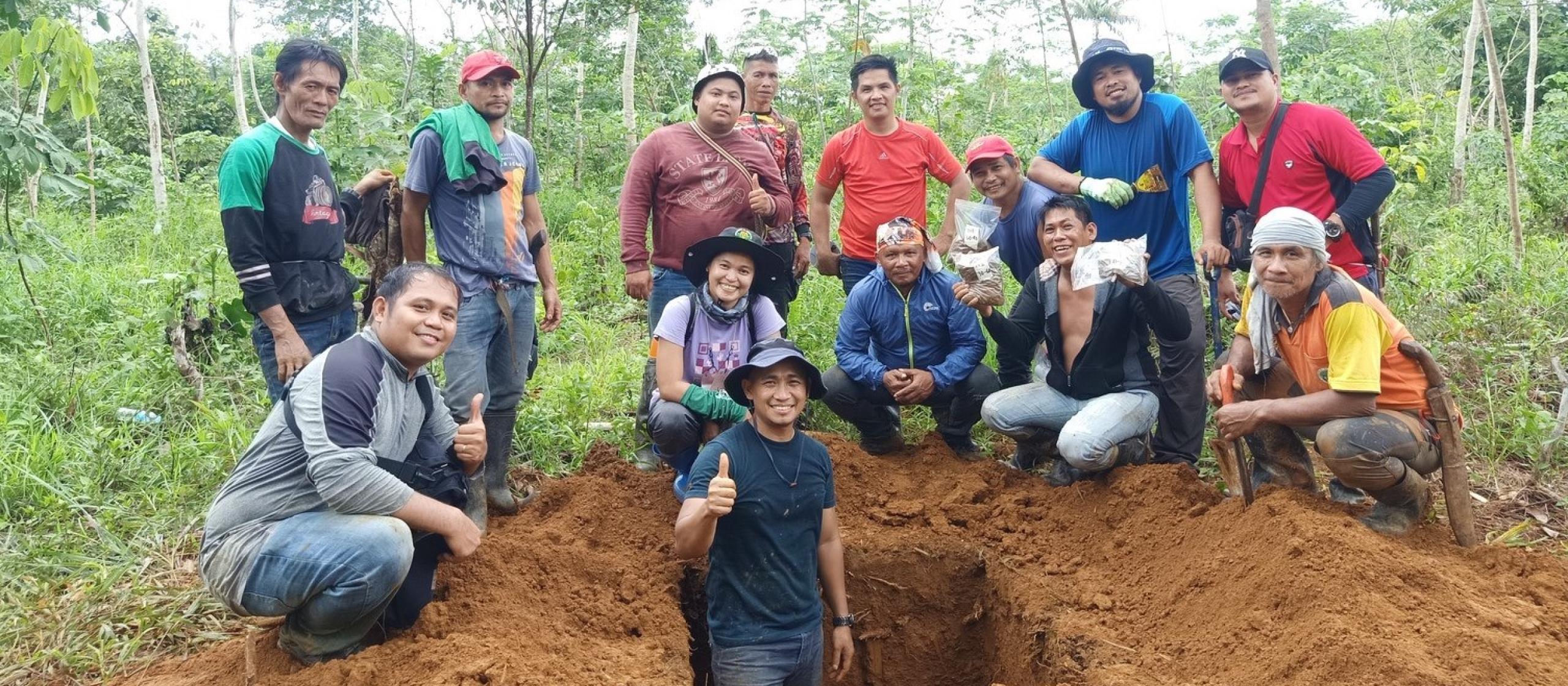 Group of people standing on a mound of soil.