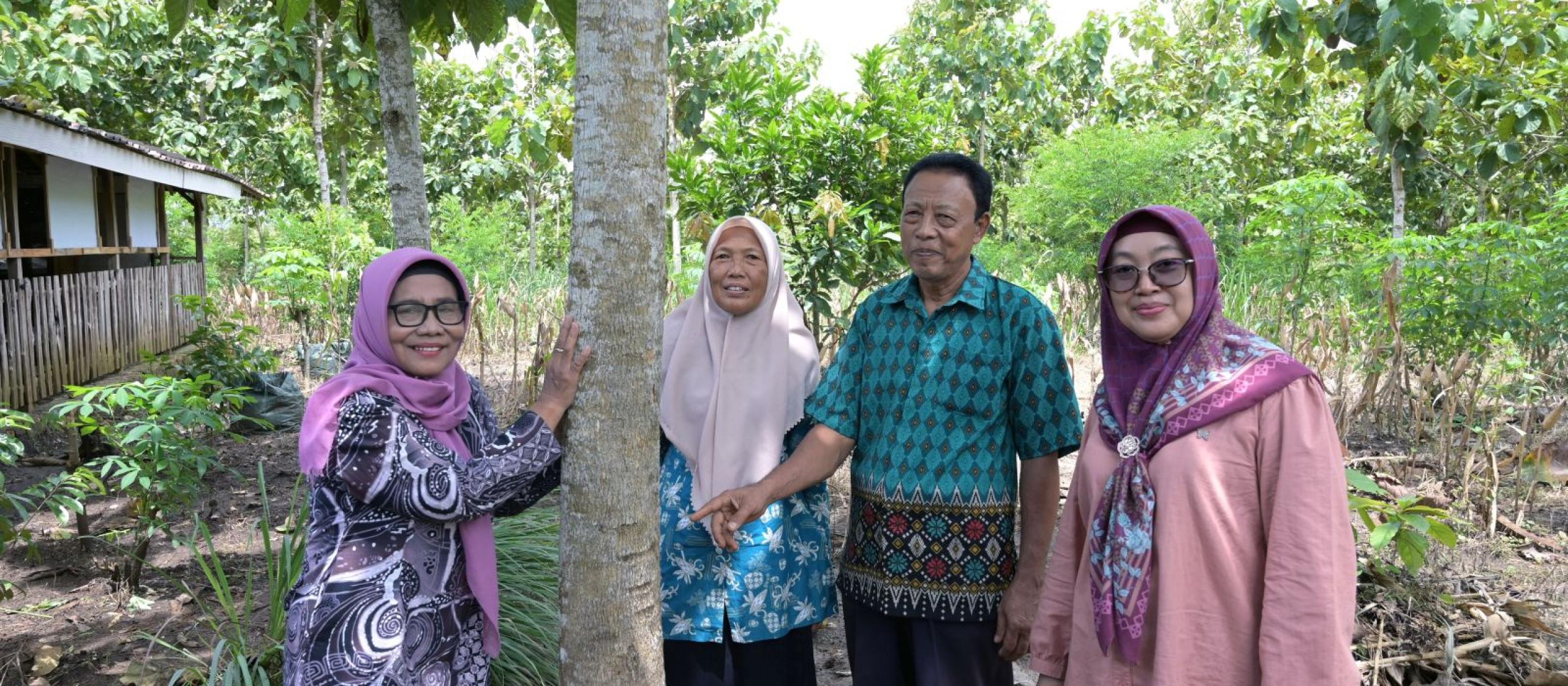 Participants gathered beside a tree during a field visit in a forest setting.