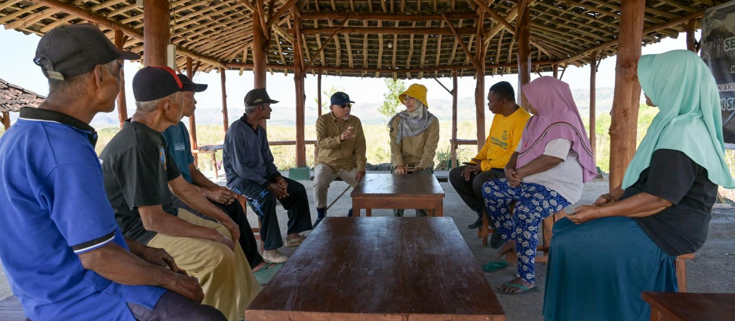 Community members and researchers meeting in an open-sided shelter to discuss local challenges and solutions.