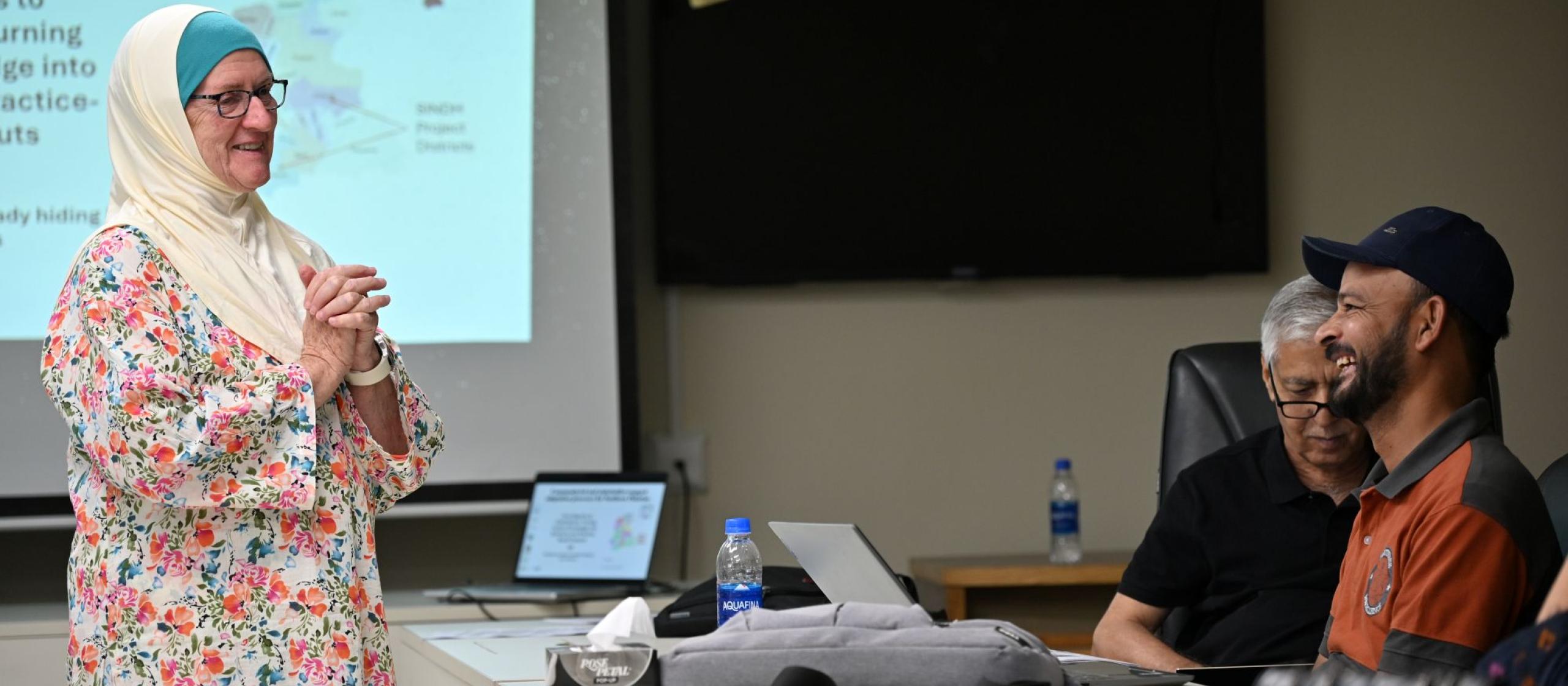 Participant speaking during a workshop while others listen around a meeting table.