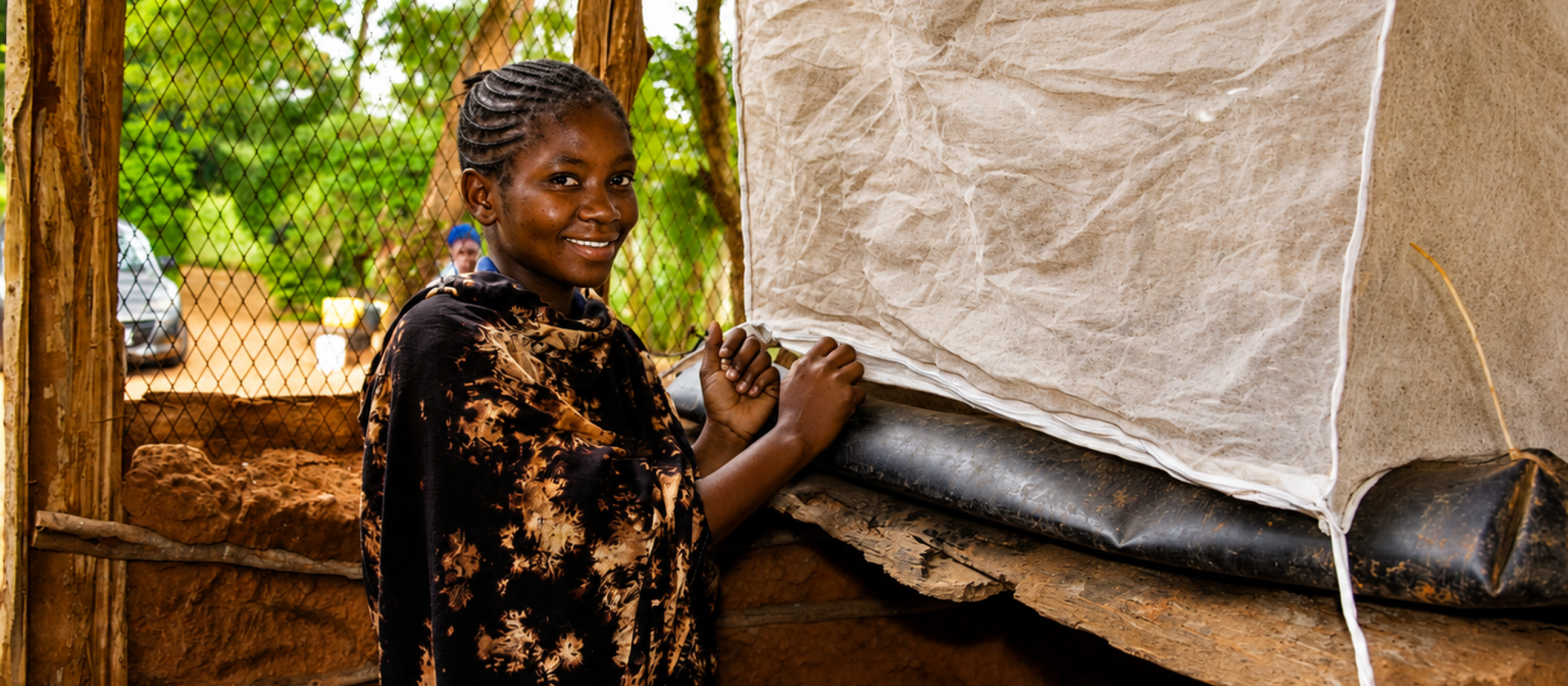 Person standing beside an insect-rearing enclosure covered with mesh fabric.