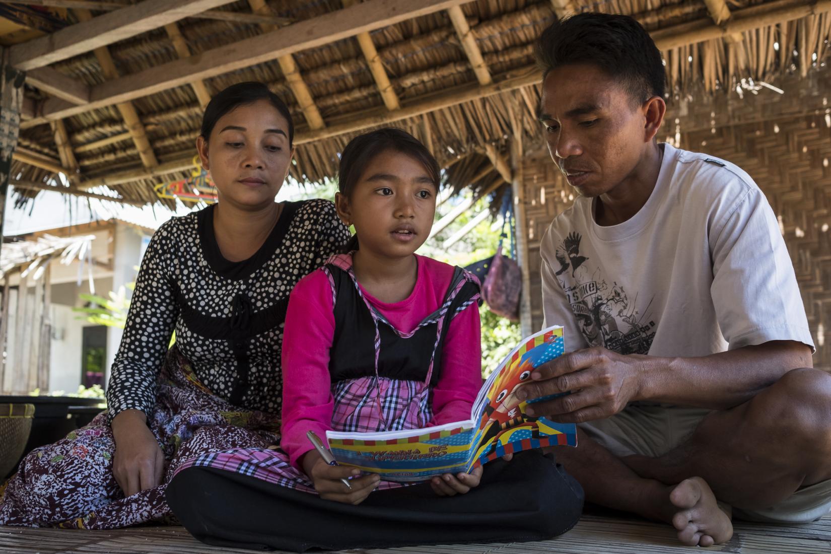 Hardiyanto and his wife read with their daughter Fauzia. Photo: Conor Ashleigh/ACIAR.