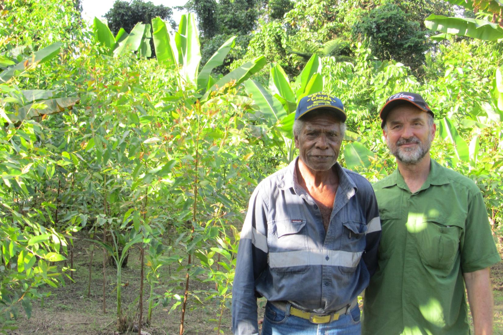 Two men stand in front of a plantation