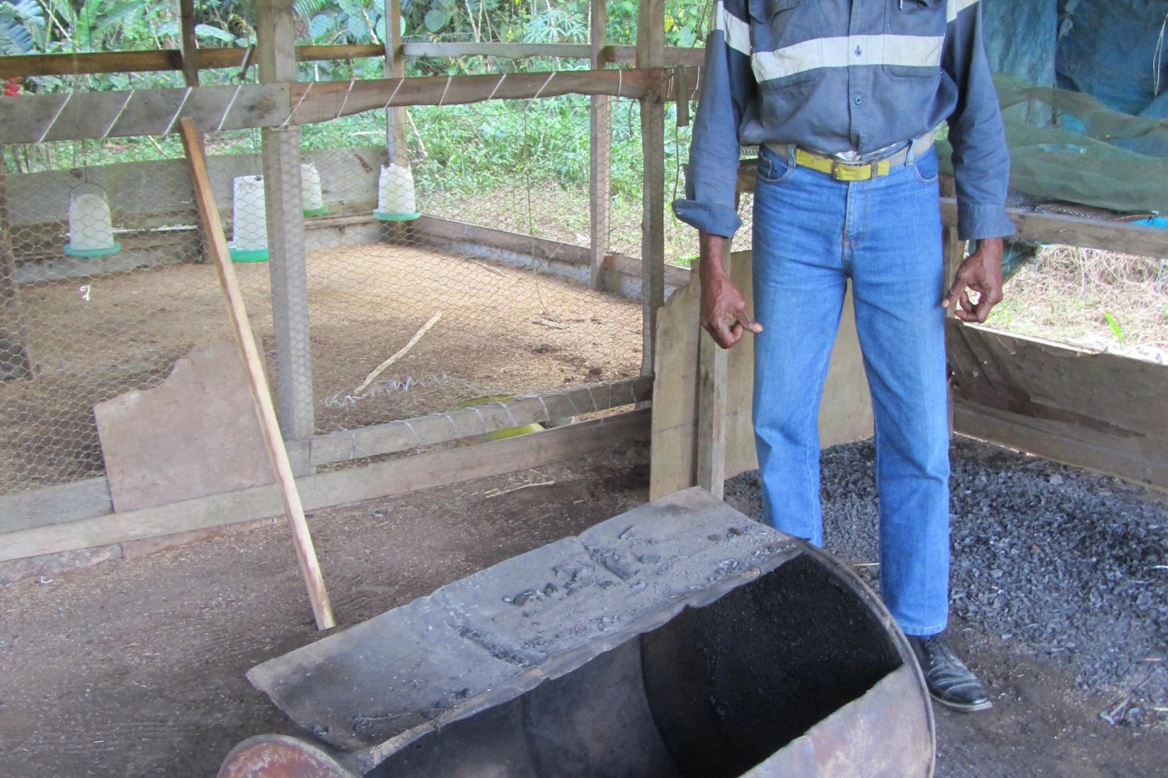 A man stands behind a charcoal fire pit