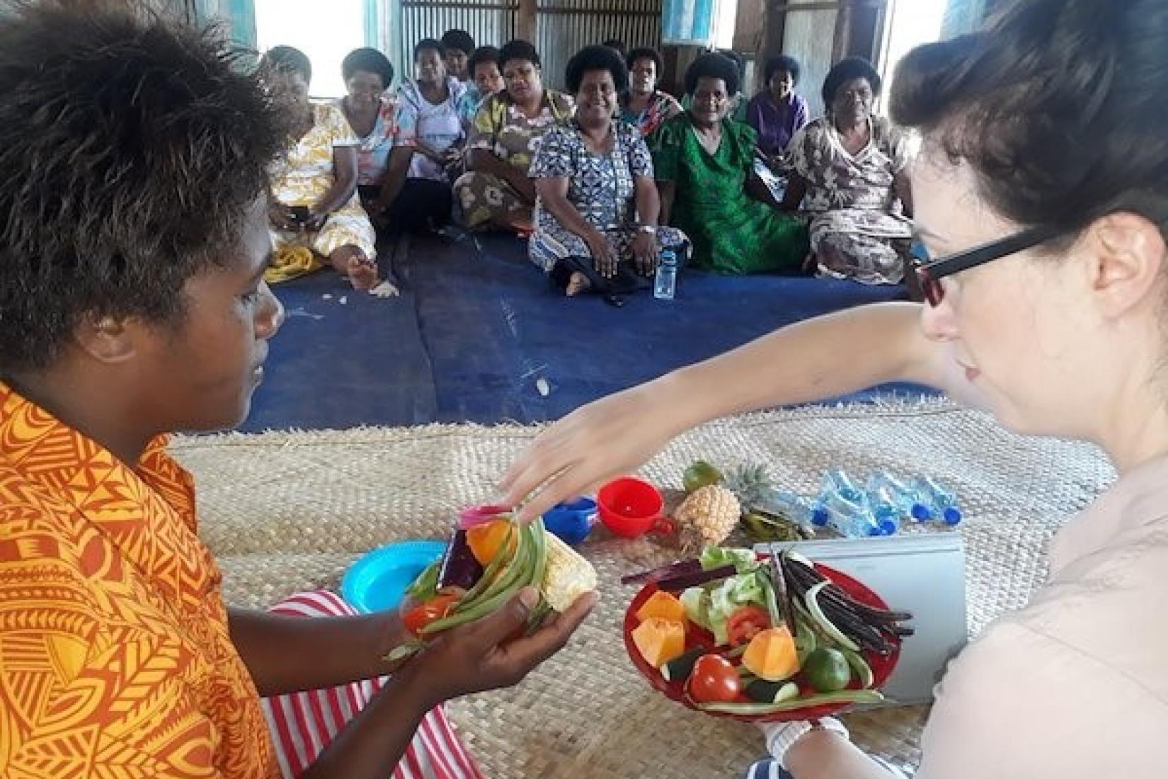 Lydia O'Meara showing a workshop participant in Fiji what foods help make up a healthy diet.