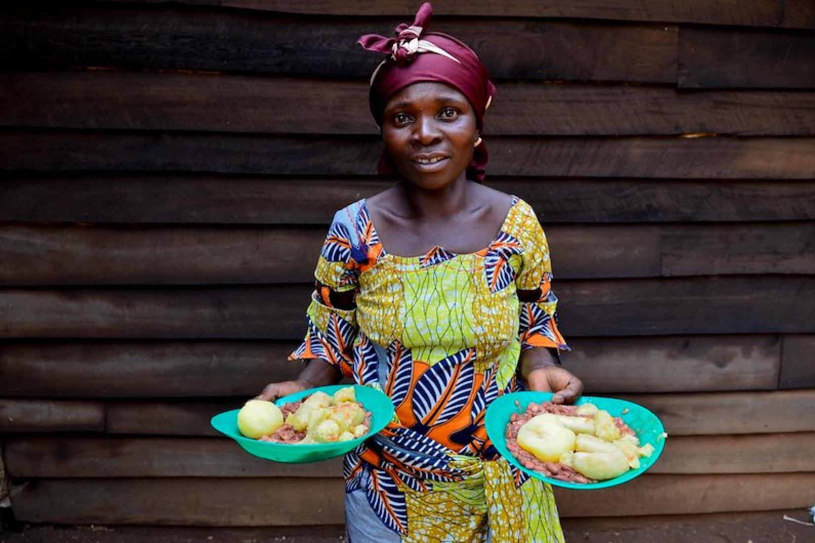 African woman holding plates of nutritious foods, including gorilla beans. Credit: CIAT