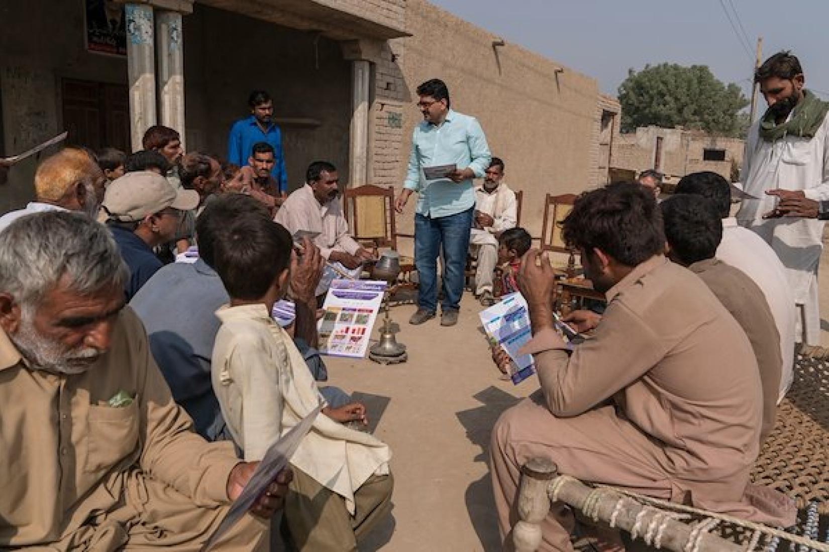 Abdul Aziz from University of Veterinary and Animal Sciences (UVAS) hands out information sheets to the farmers from 96D village in rural Punjab Province. Image: ACIAR/Conor Ashleigh