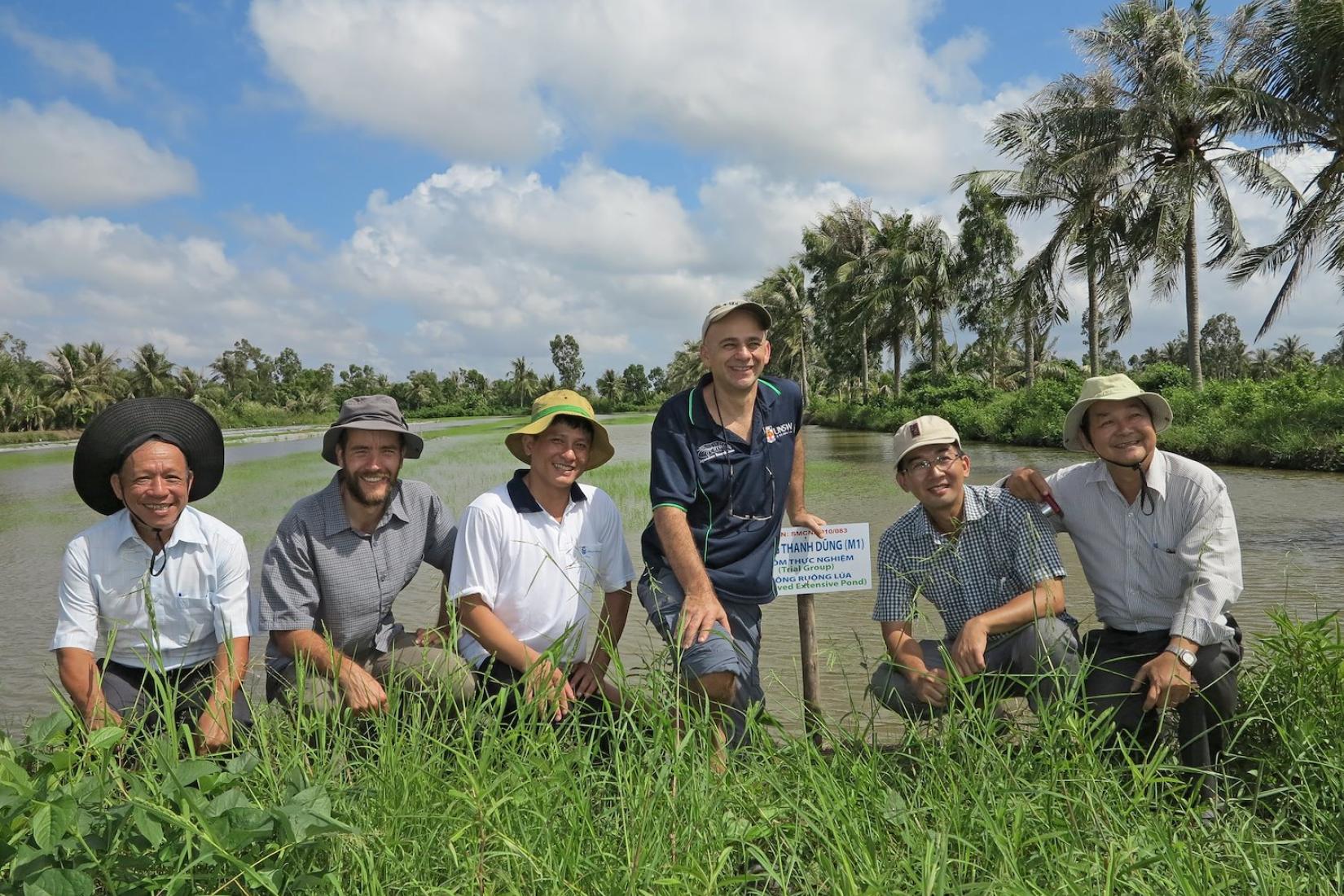 Six men in front of a rice-shrimp crop which is in water