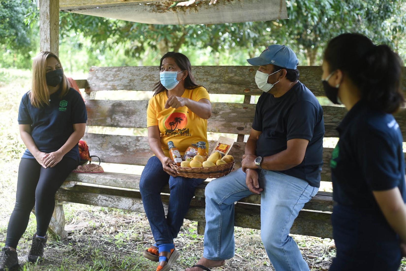Researchers sitting with a mango farmer 