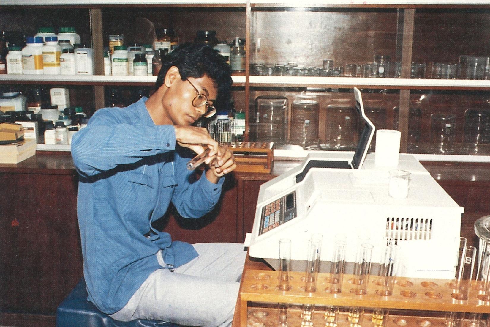 Man in lab pouring liquid between test tubes