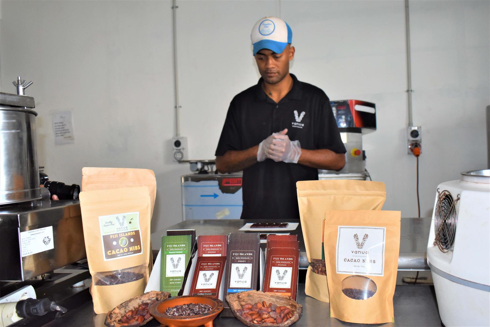 Man standing behind counter of chocolate and beans