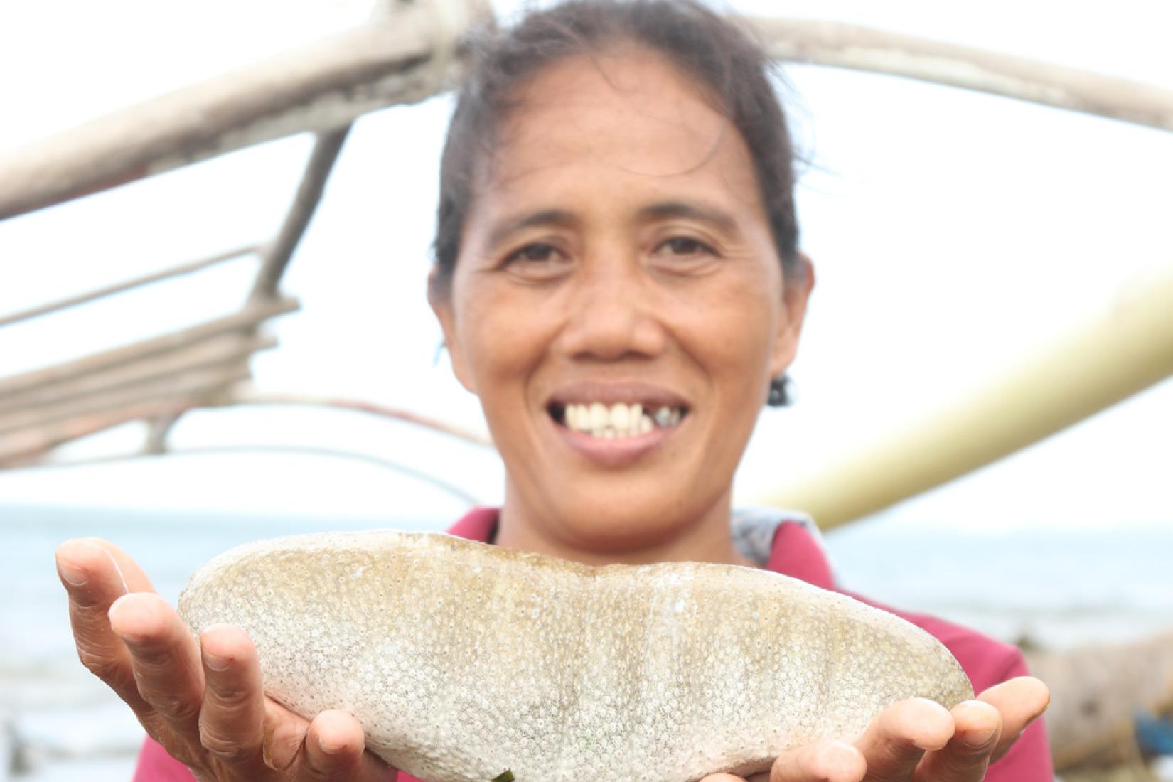Jessica Macawile holds up her sandfish harvest in Maliwaliw Island, Guiuan, Eastern Samar