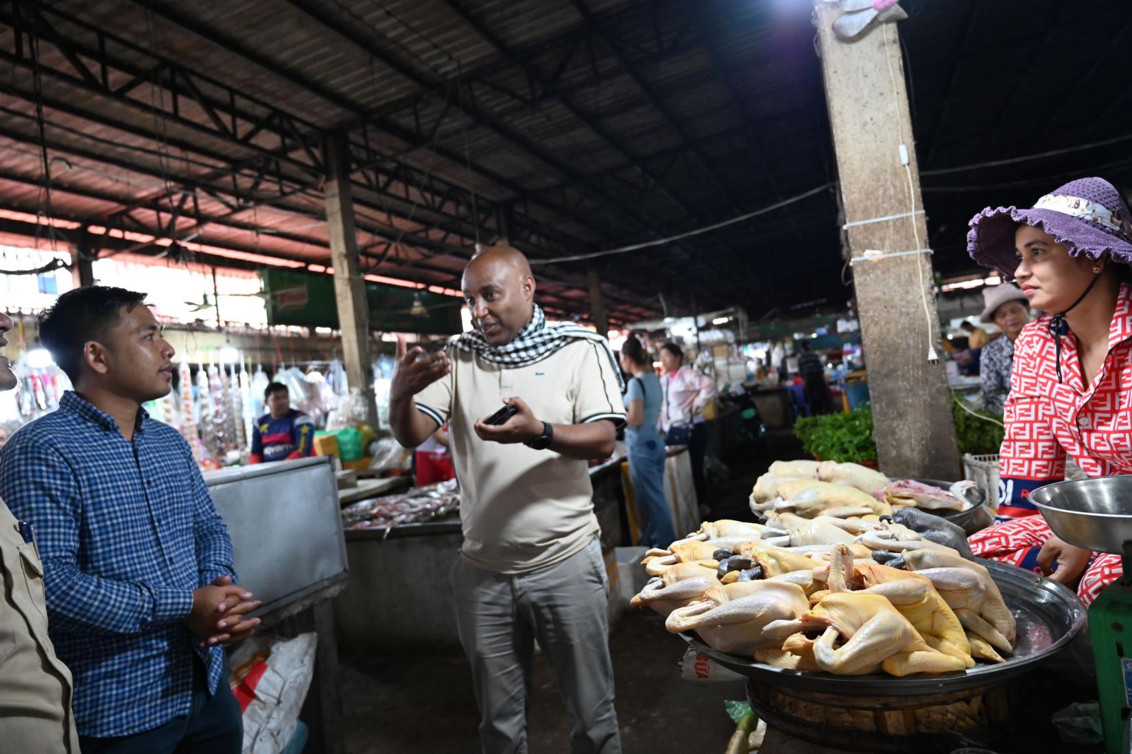 People talking standing near fresh chicken vendor in markets. 