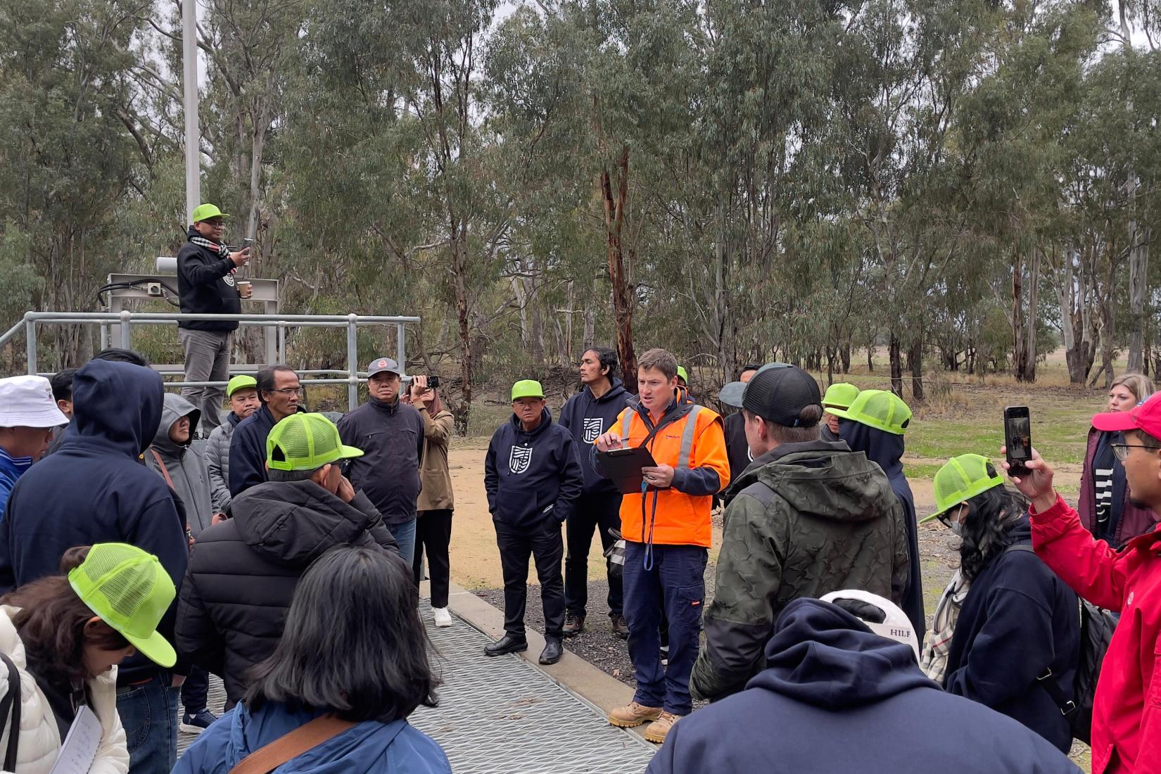 A large group of people outside standing over a metal structure