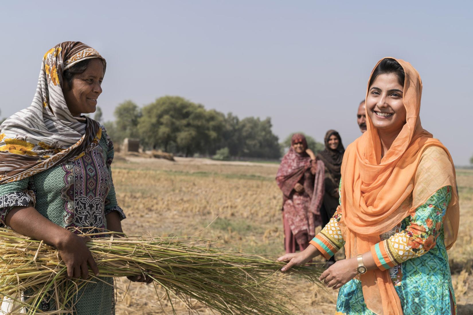 Project researcher, Anam Afzal (right) with a female farmer examining fodder used to feed livestock.