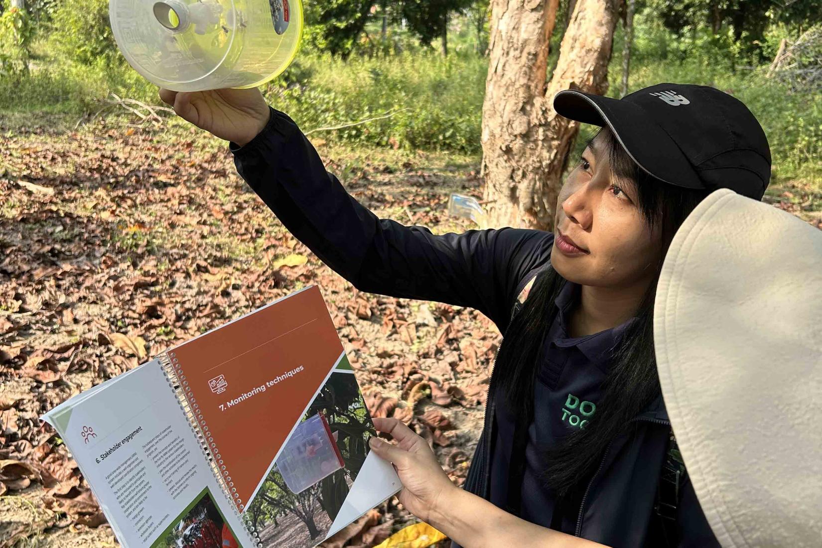Workshop participants use the newly launched training guide and field manual to hang traps that attract male fruit fly. Photo: ACIAR