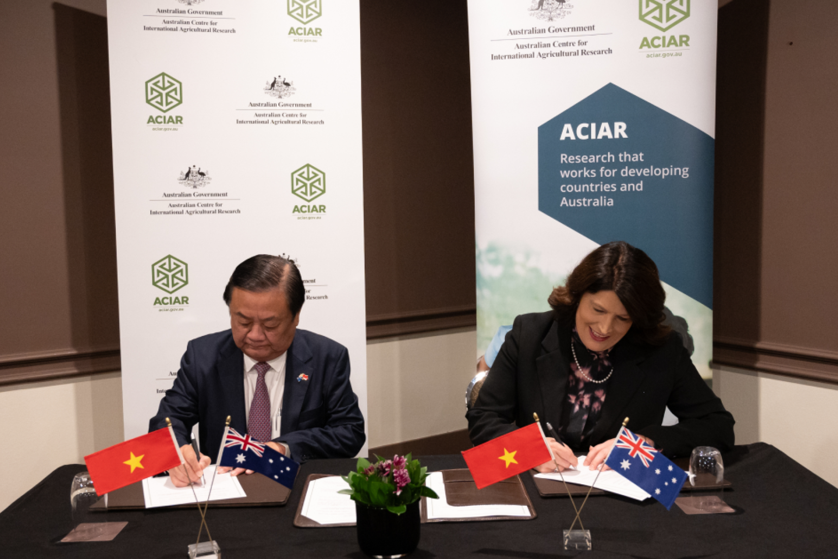 Man and woman sitting at table signing documents