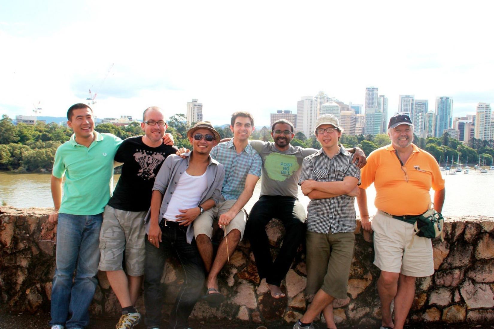 Group of men standing in a row on a stone wall.