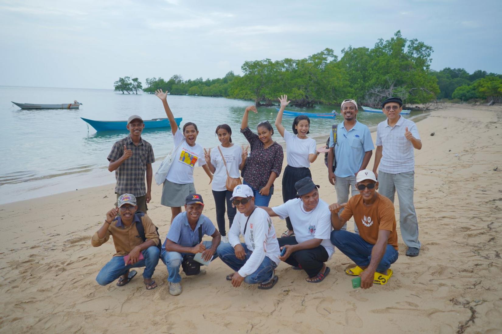 Group of people standing on the sand near the water