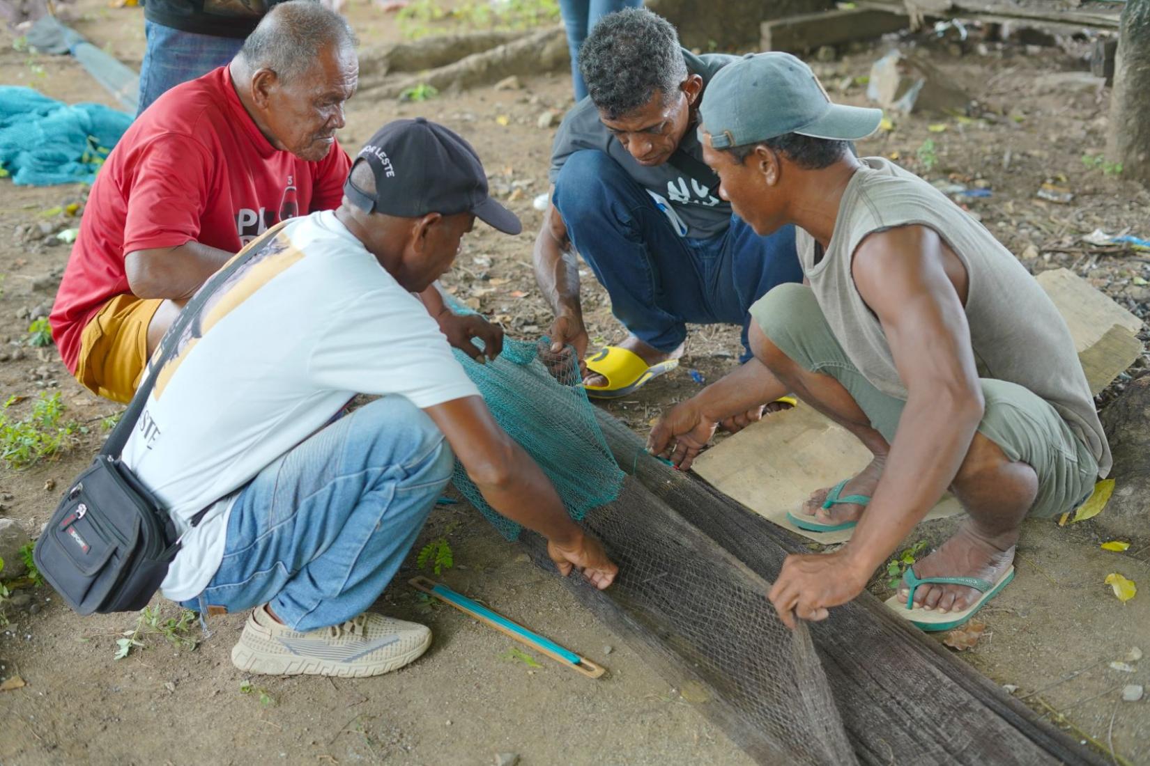 Men crouching down and working with fishing gear