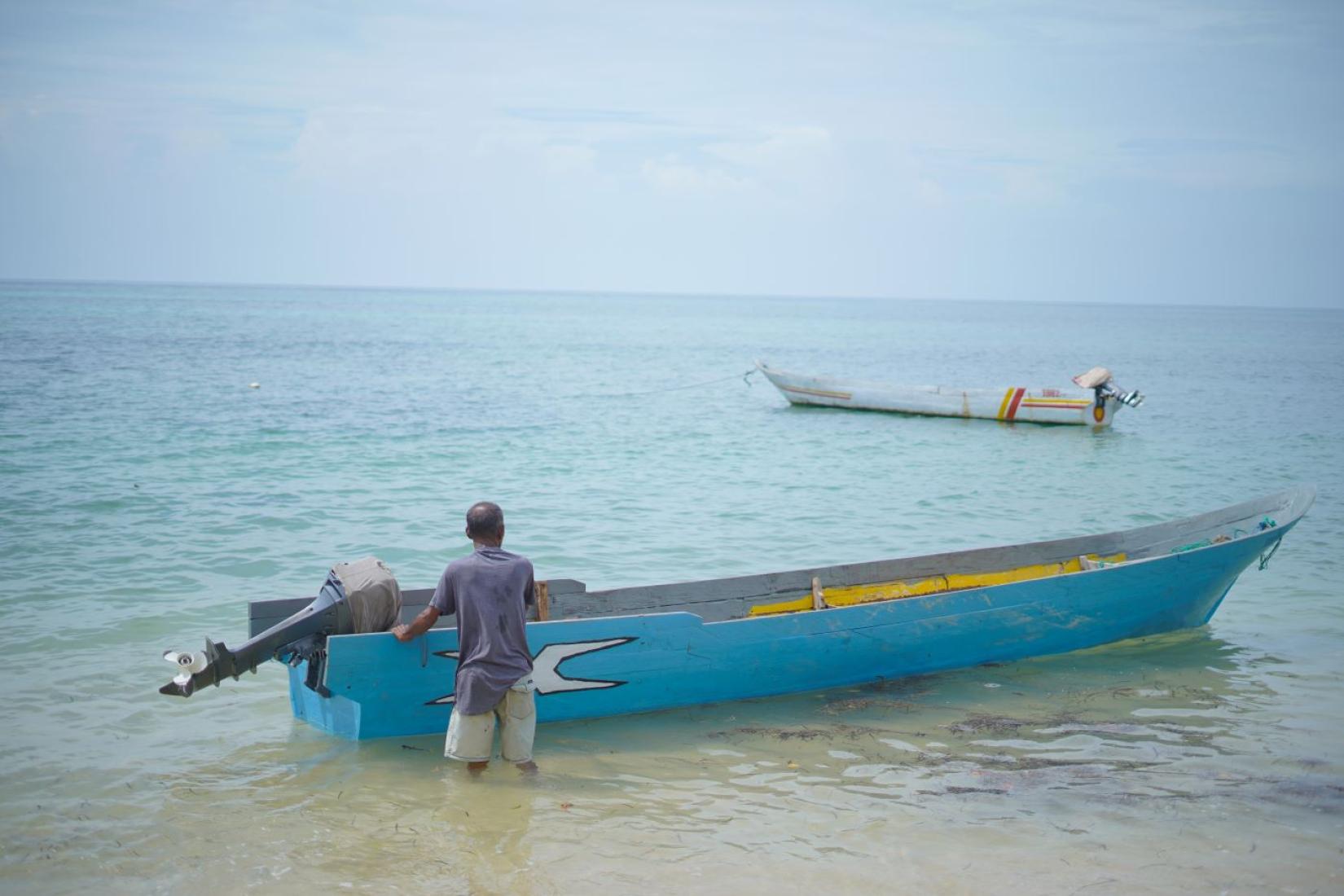 Man standing in water next to a boat
