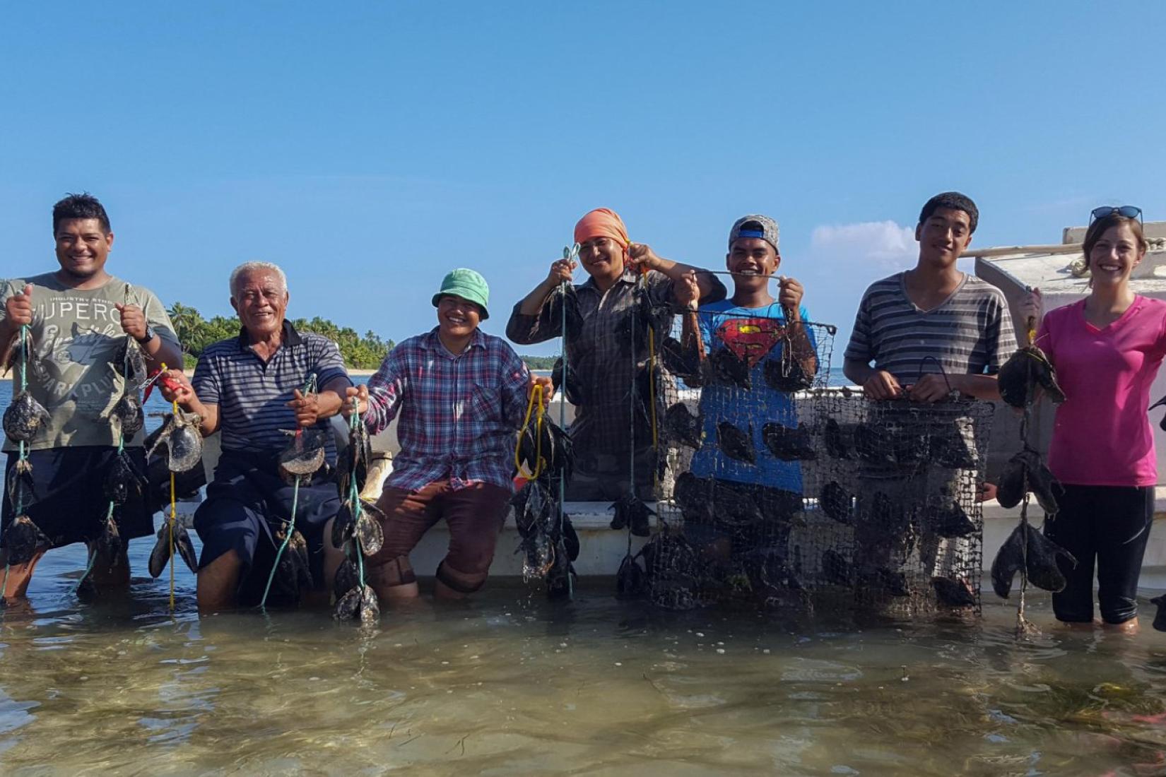 Group of people standing in the water holding oysters