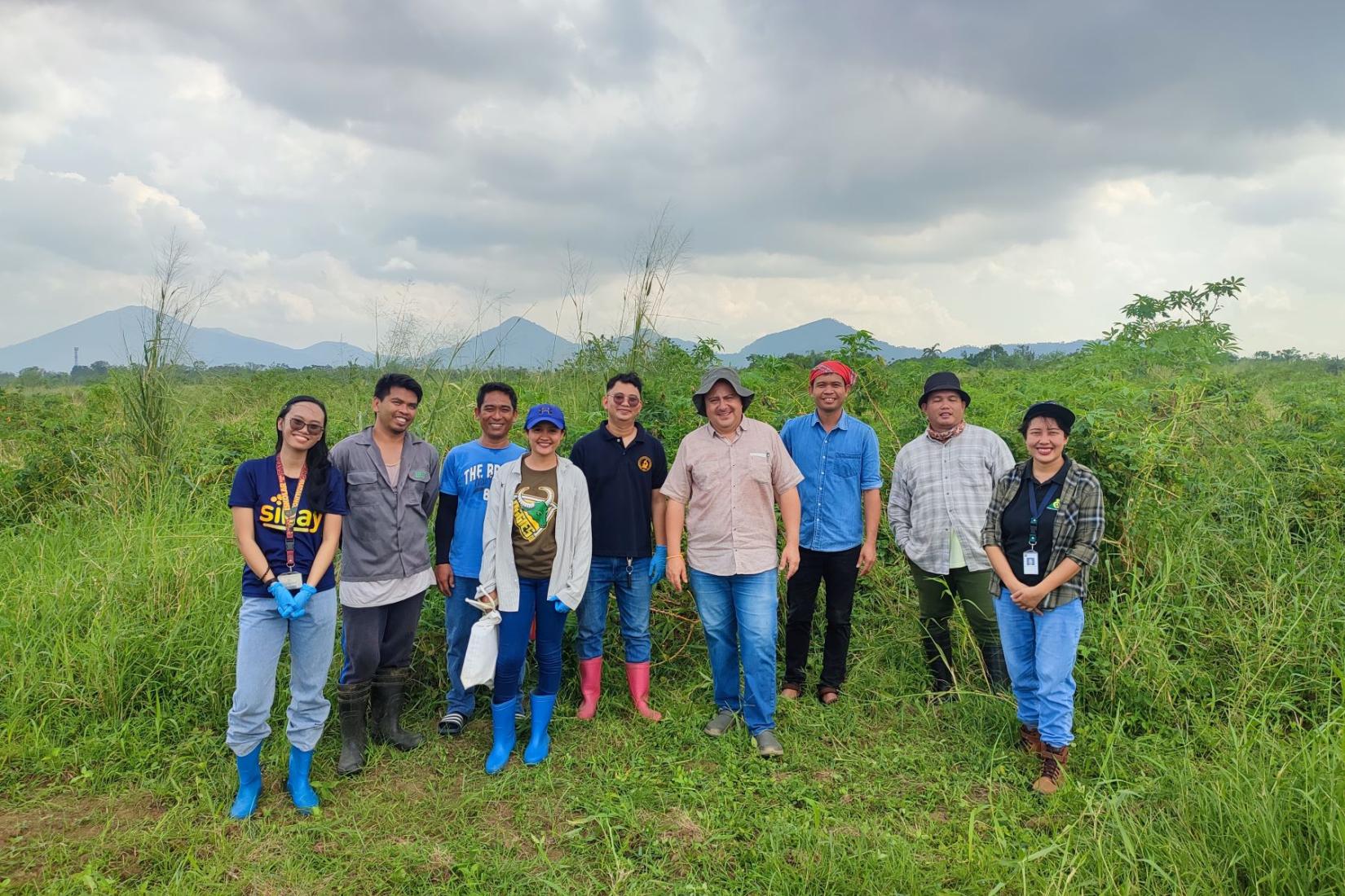 A group of people standing in a green field facing the camera