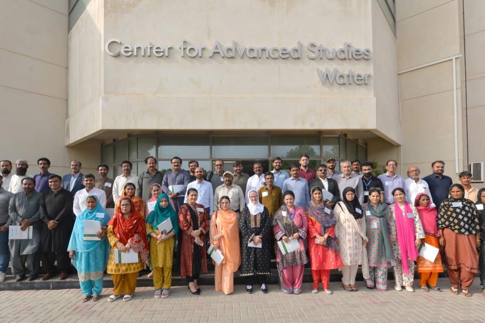 A large group of people standing together outside the Center for Advanced Studies in Water, posing for a group photo at the building entrance.