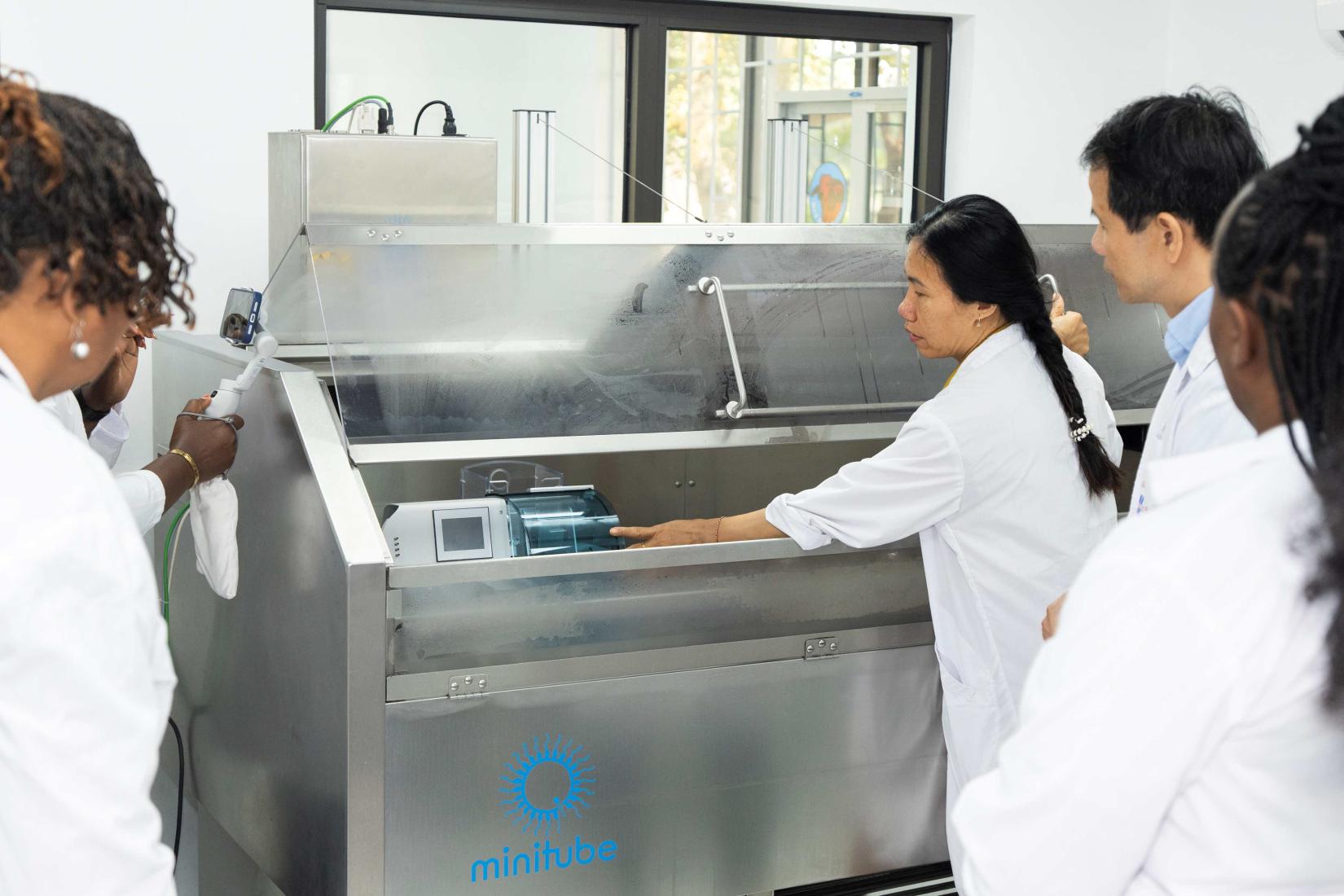 Researchers in lab coats observing equipment during a laboratory demonstration.