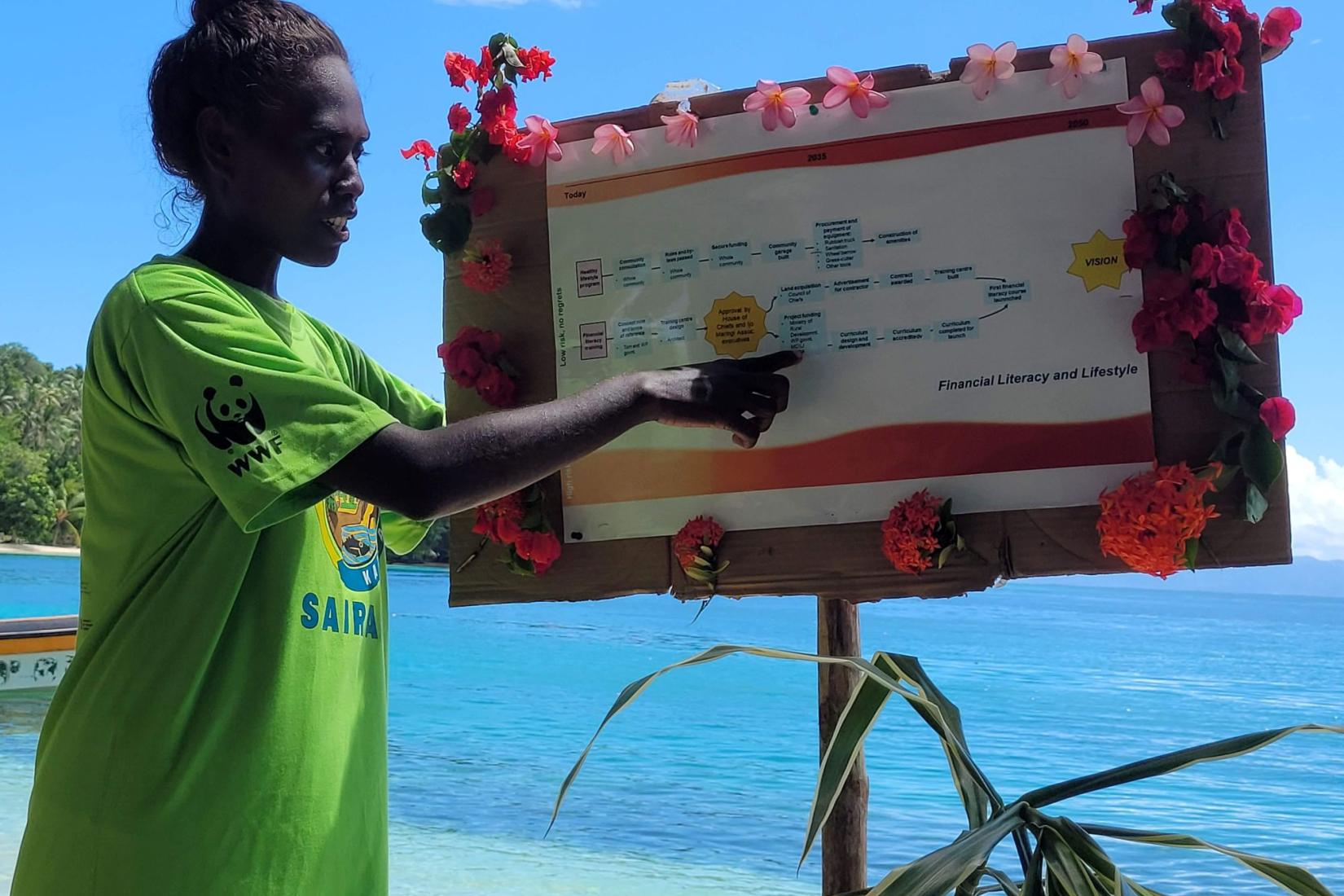 Community member presents a planning roadmap board beside the ocean.