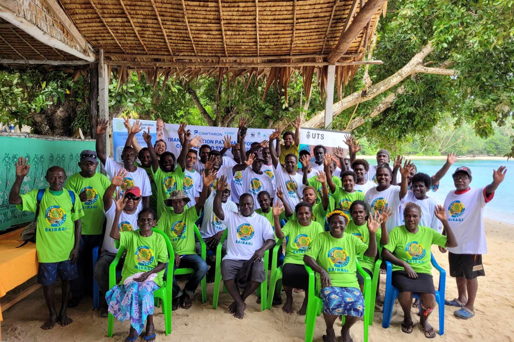 Community group gathered outdoors by the beach during a mangrove conservation workshop