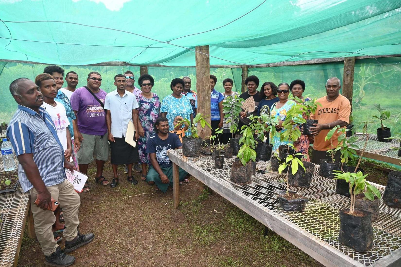 Community members gathered in a plant nursery with seedlings.