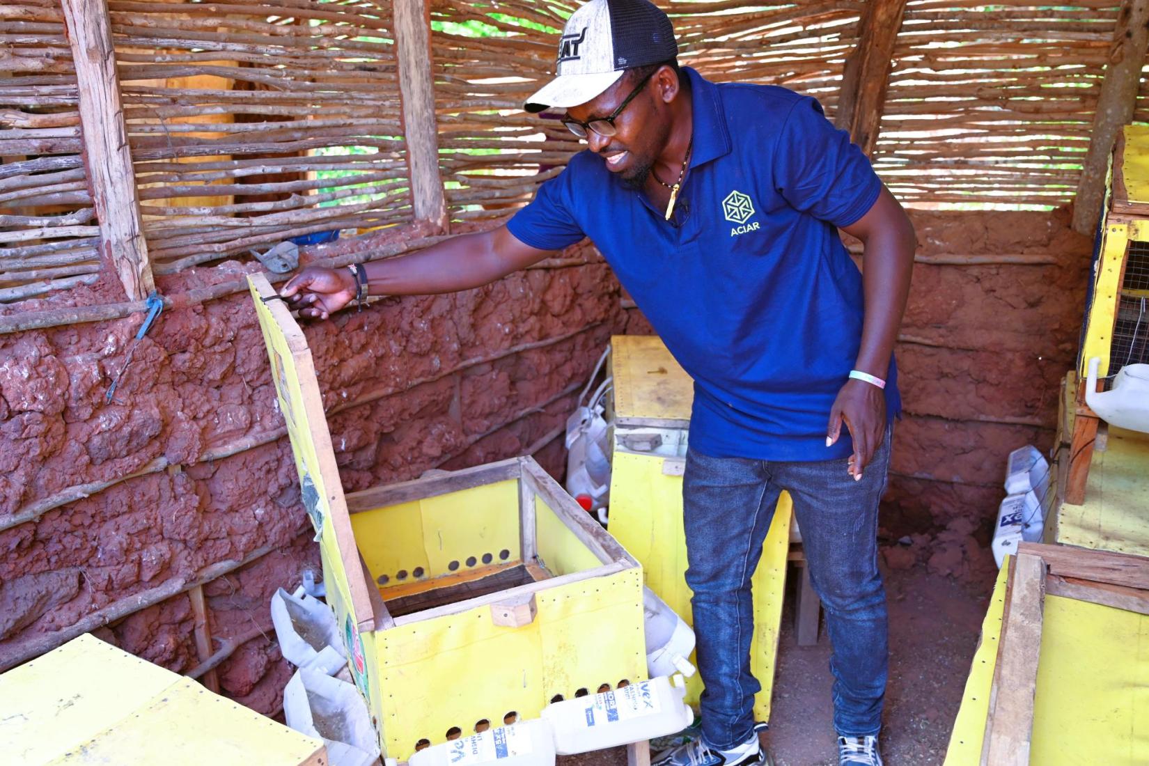 Facilitator demonstrating poultry equipment inside a small livestock shelter.