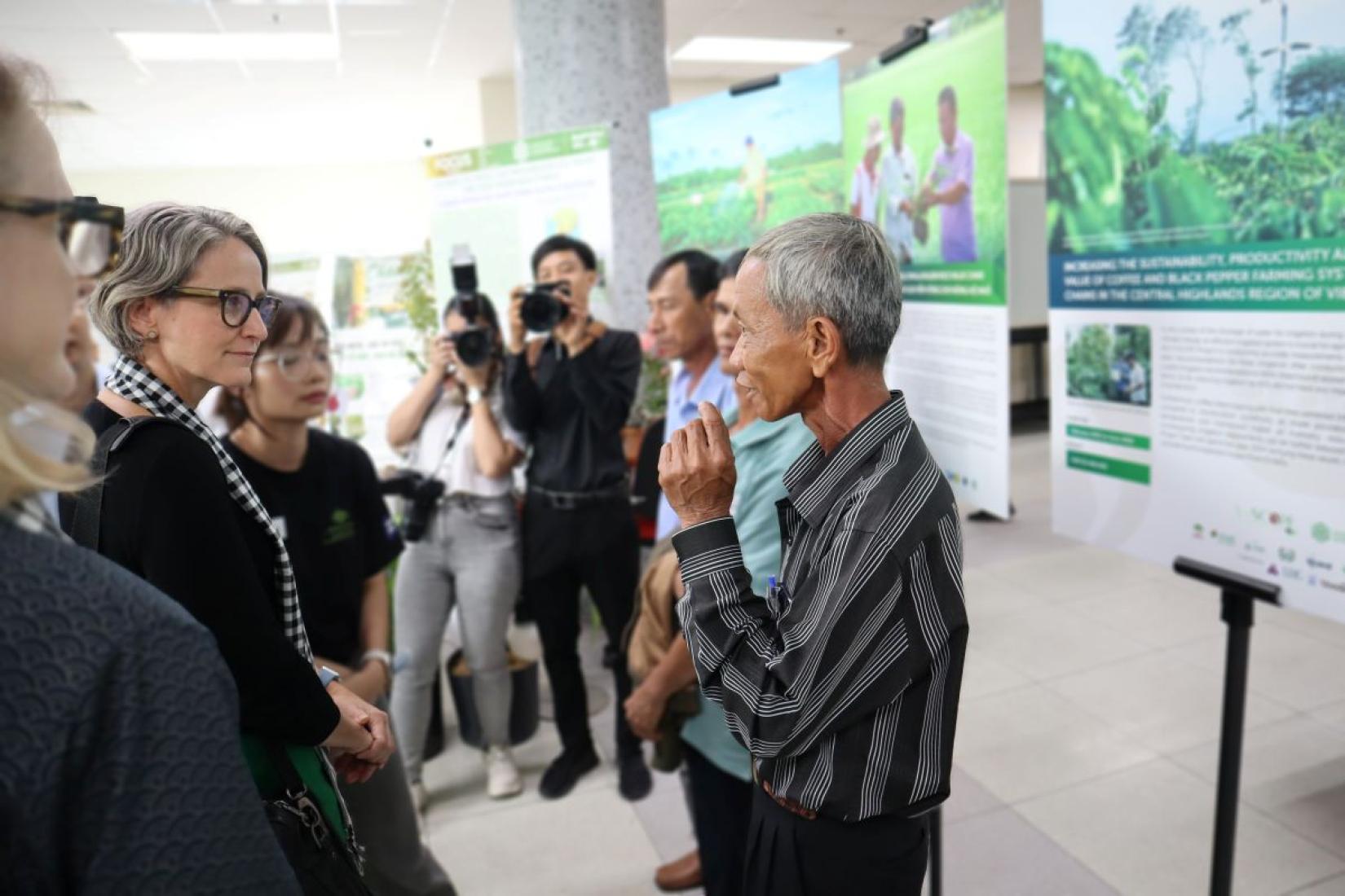Group of people viewing and discussing agricultural research posters at an exhibition display.